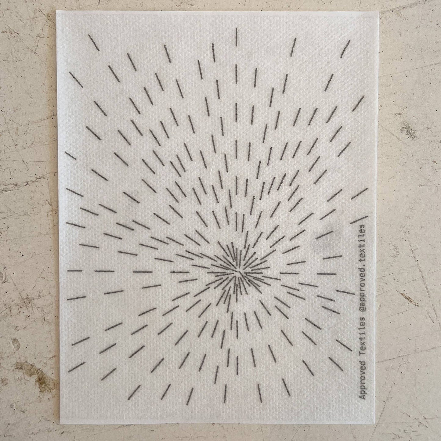 Textile swatch with a starburst pattern on a neutral background