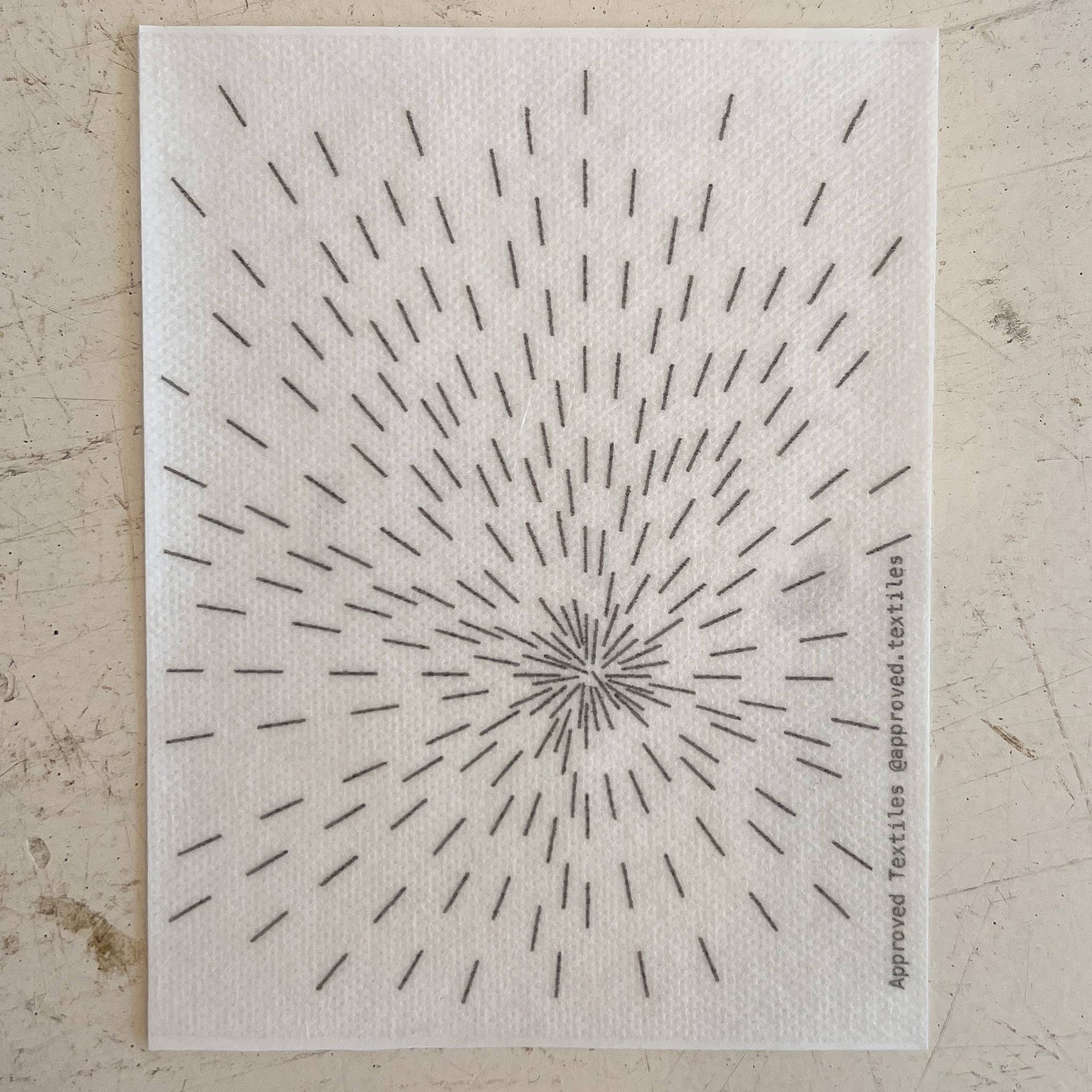 Textile swatch with a starburst pattern on a neutral background
