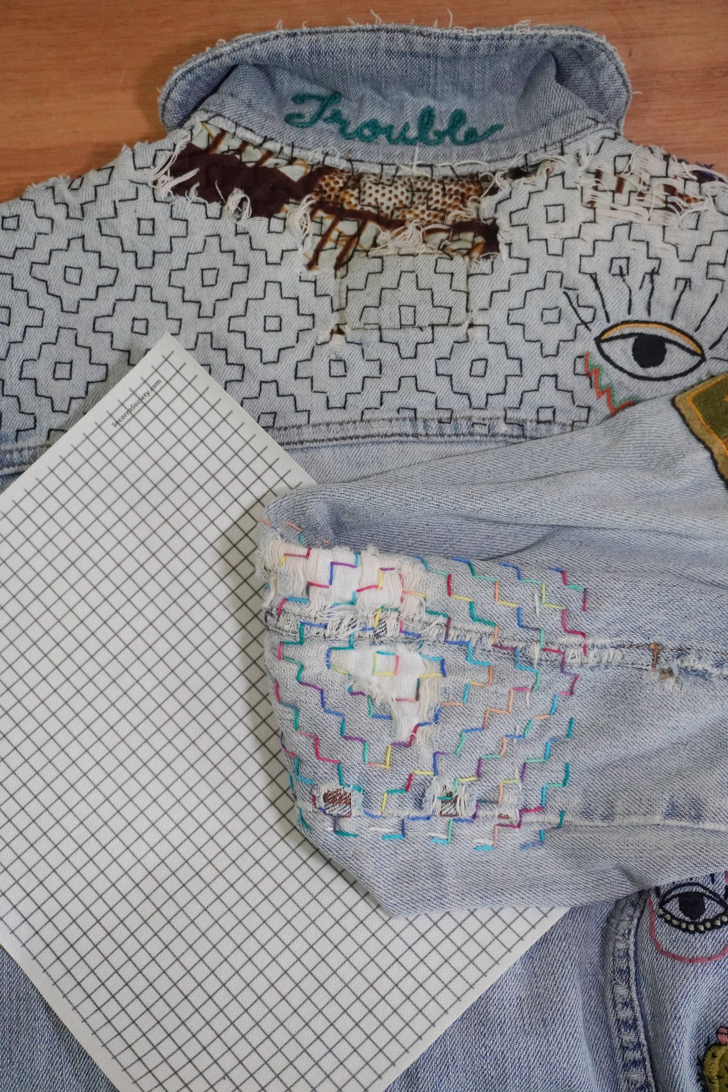 Denim jacket with embroidered designs on a wooden surface