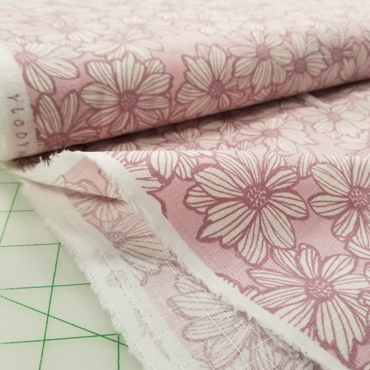 Stack of pink floral fabric swatches on a cutting mat