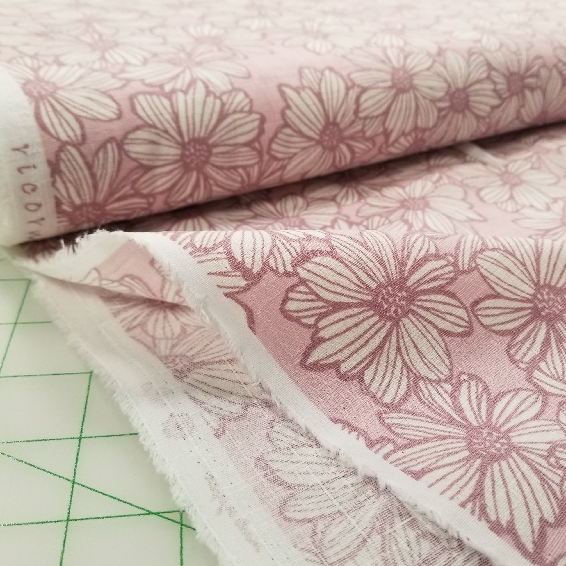 Stack of pink floral fabric swatches on a cutting mat