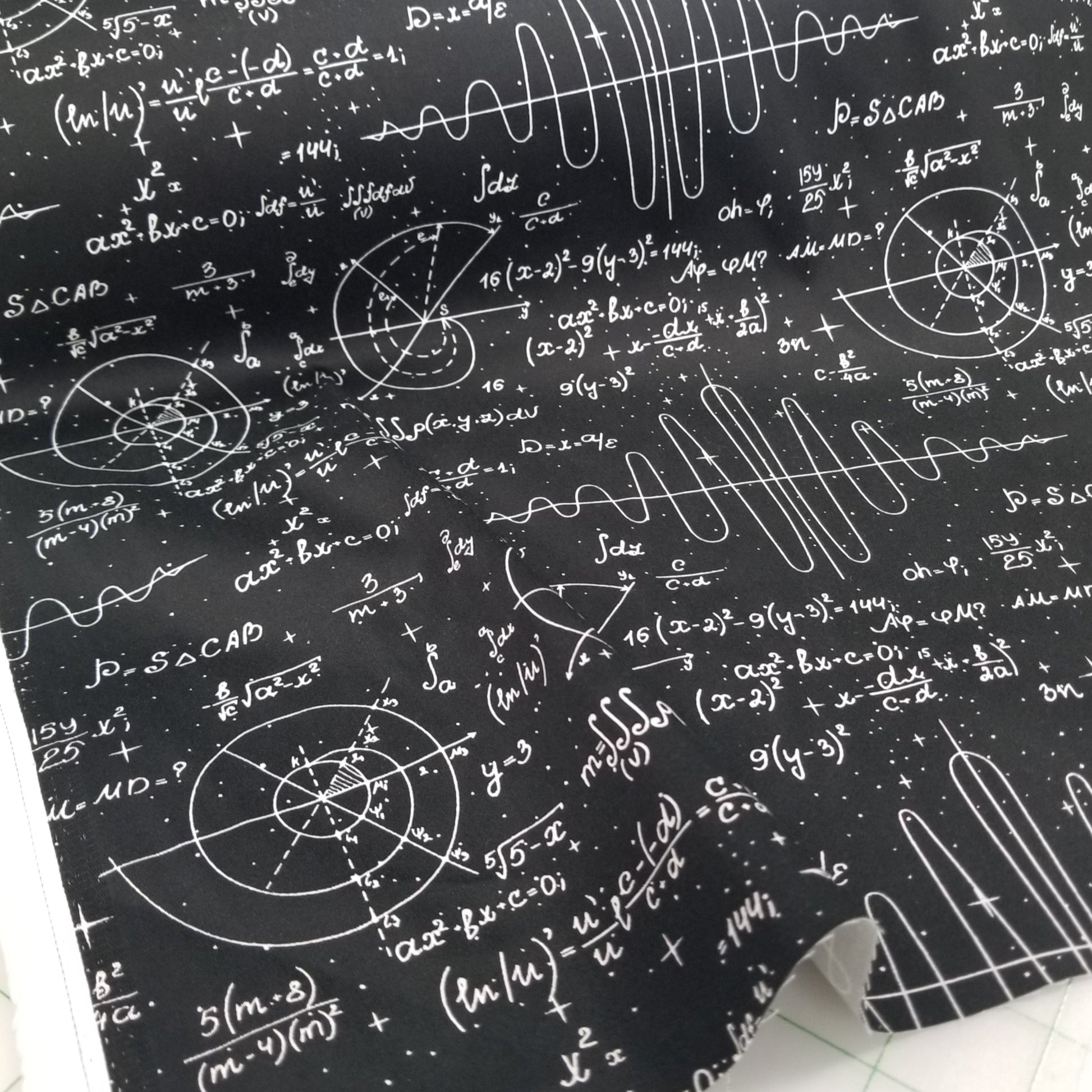 Black fabric with white mathematical equations and symbols on a white surface