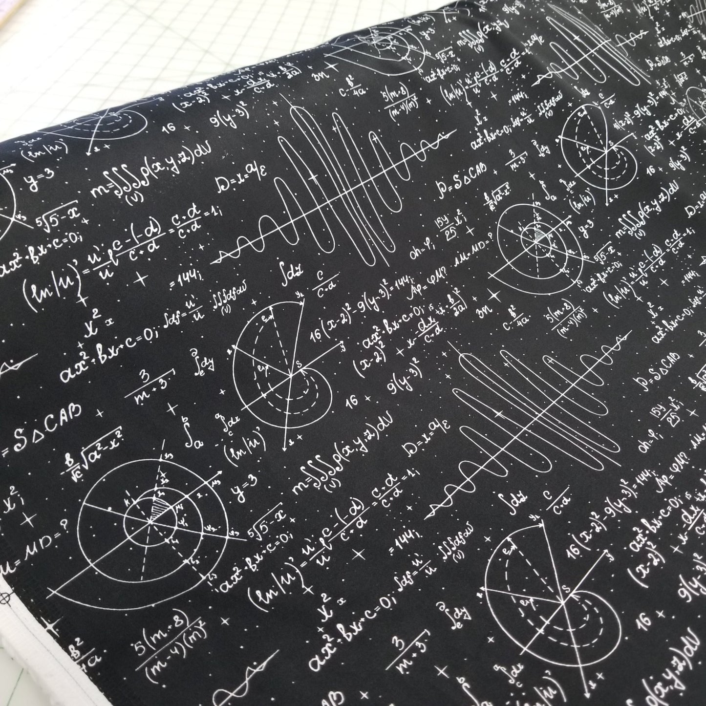 Textile with mathematical equations and symbols on a black background