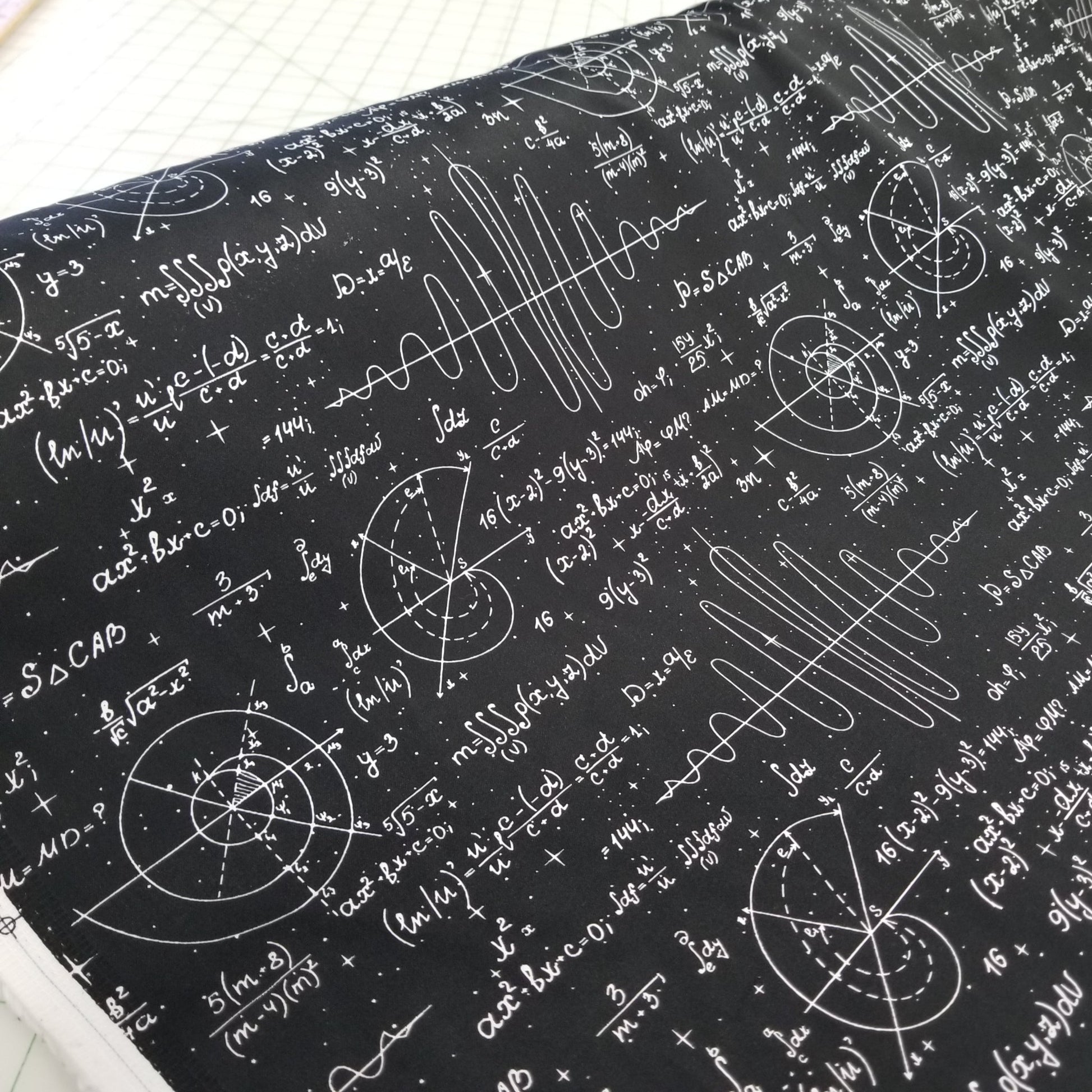 Textile with mathematical equations and symbols on a black background