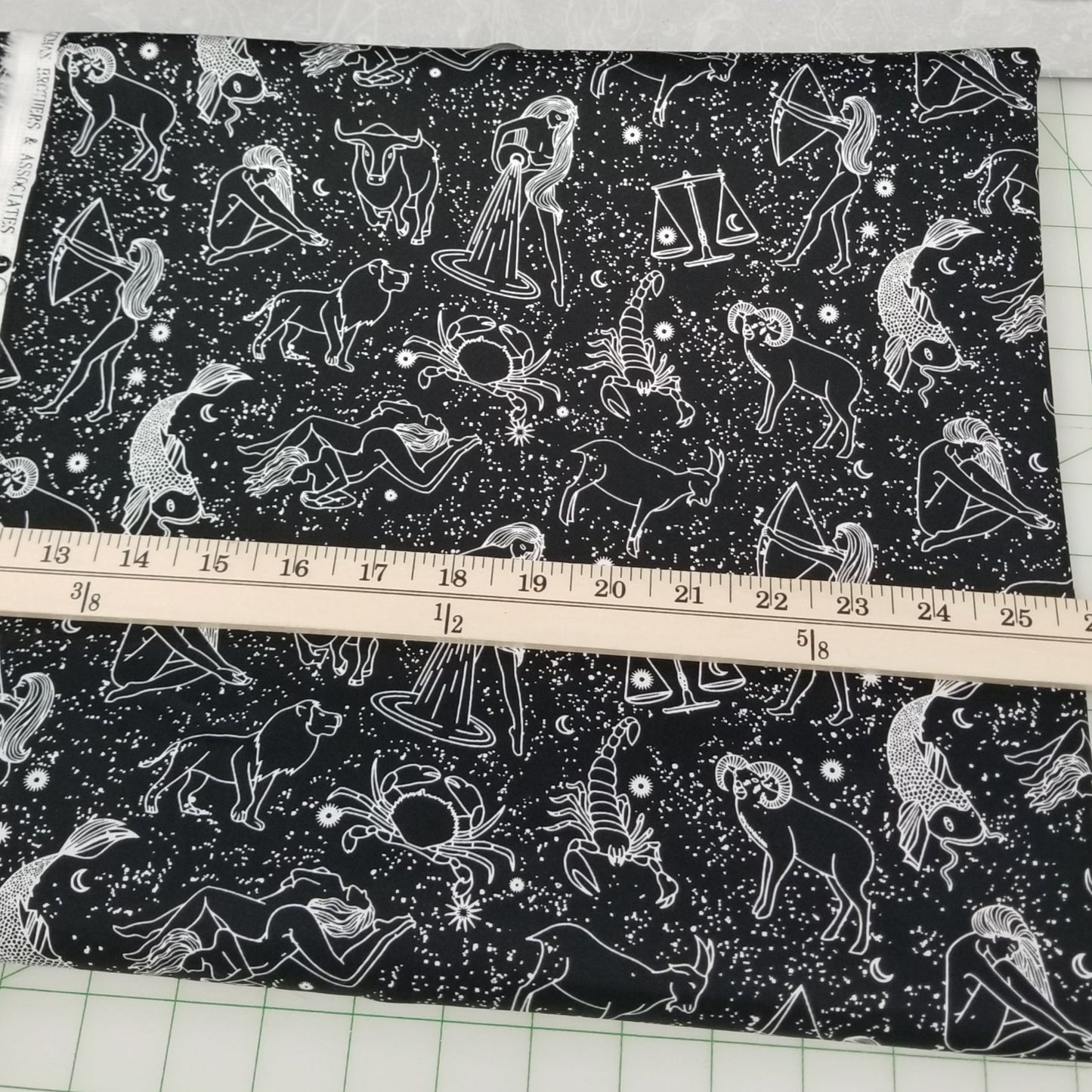 Fabric with zodiac pattern being measured with a ruler on a grid background