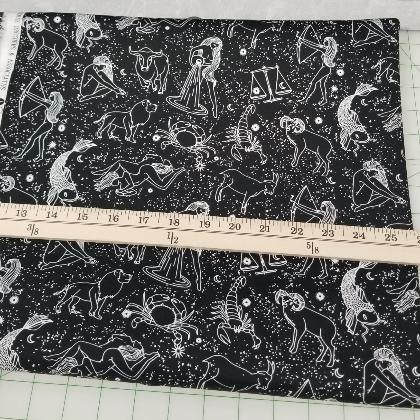 Fabric with zodiac pattern being measured with a ruler on a grid background