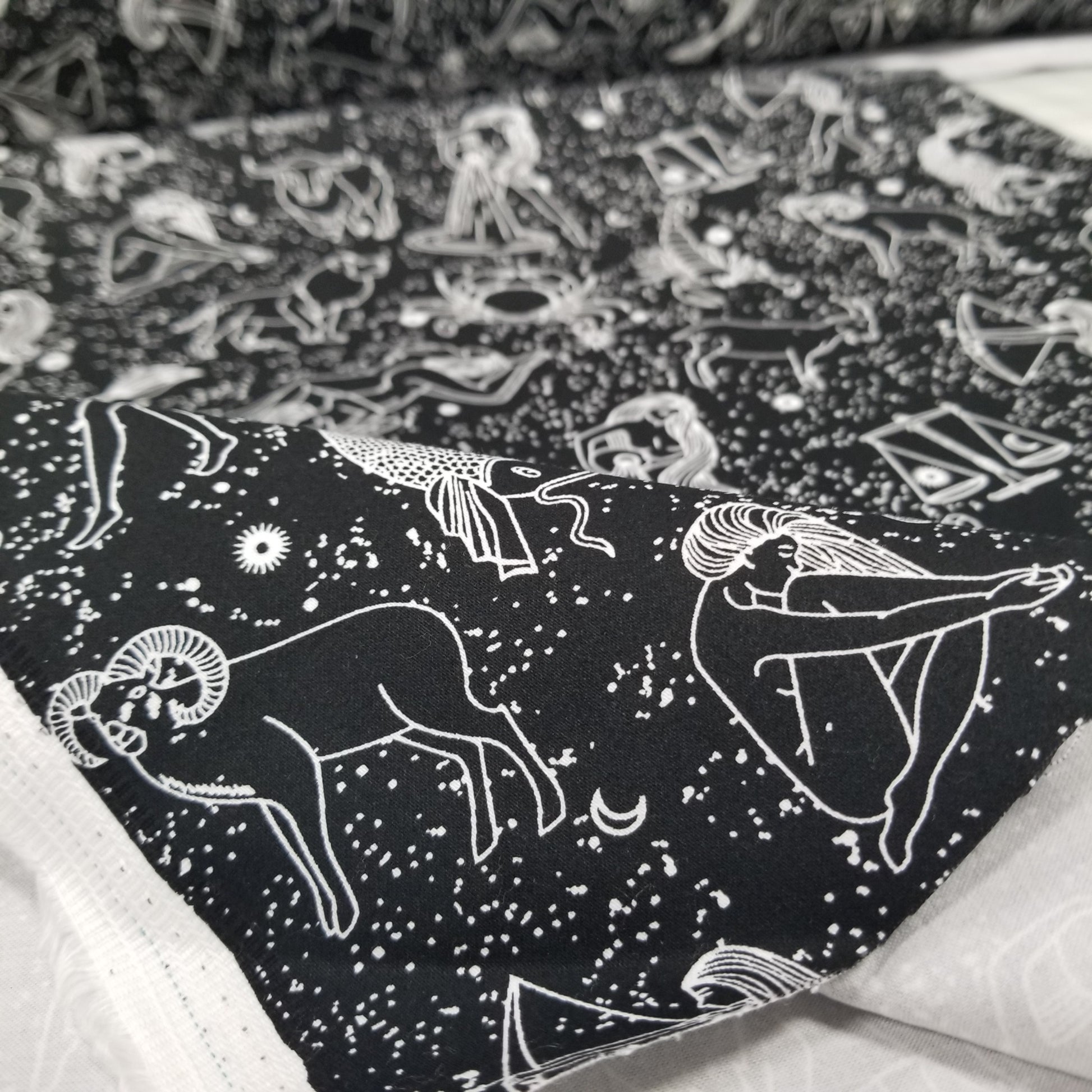 Black shirt with white astrological sign designs on a textured background
