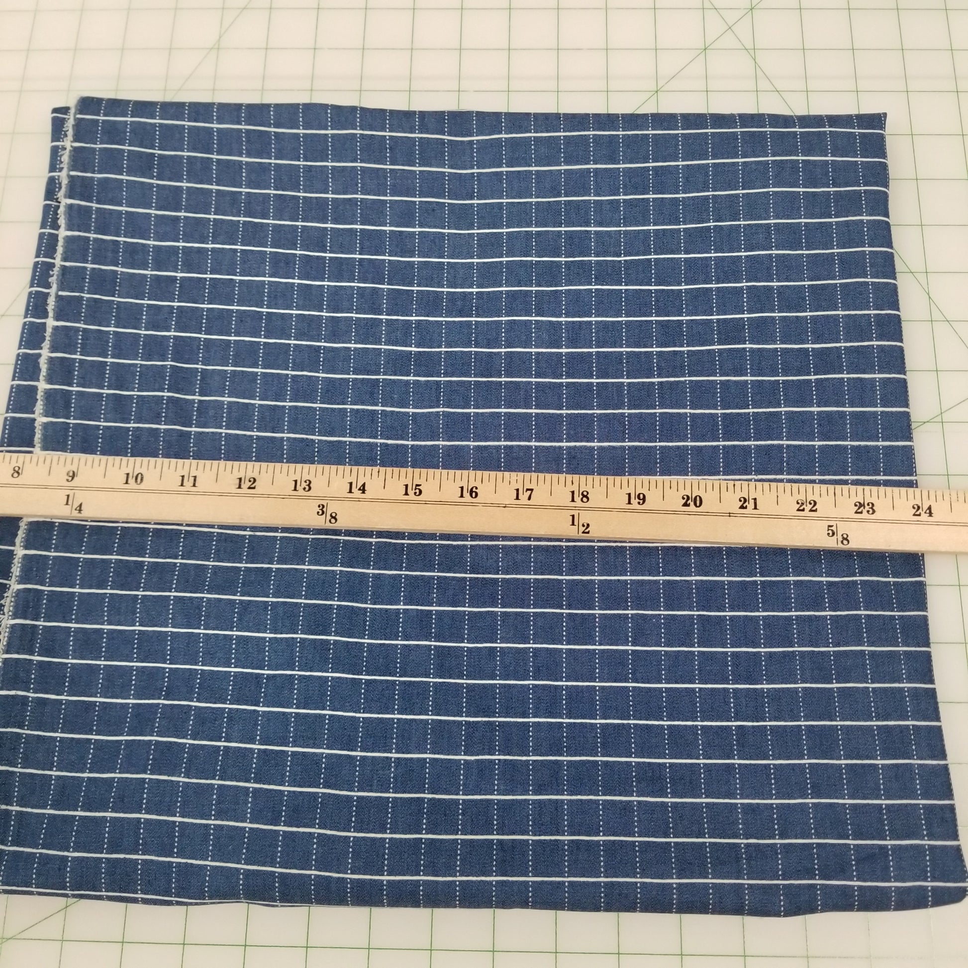 Blue checkered fabric with a ruler on a grid background
