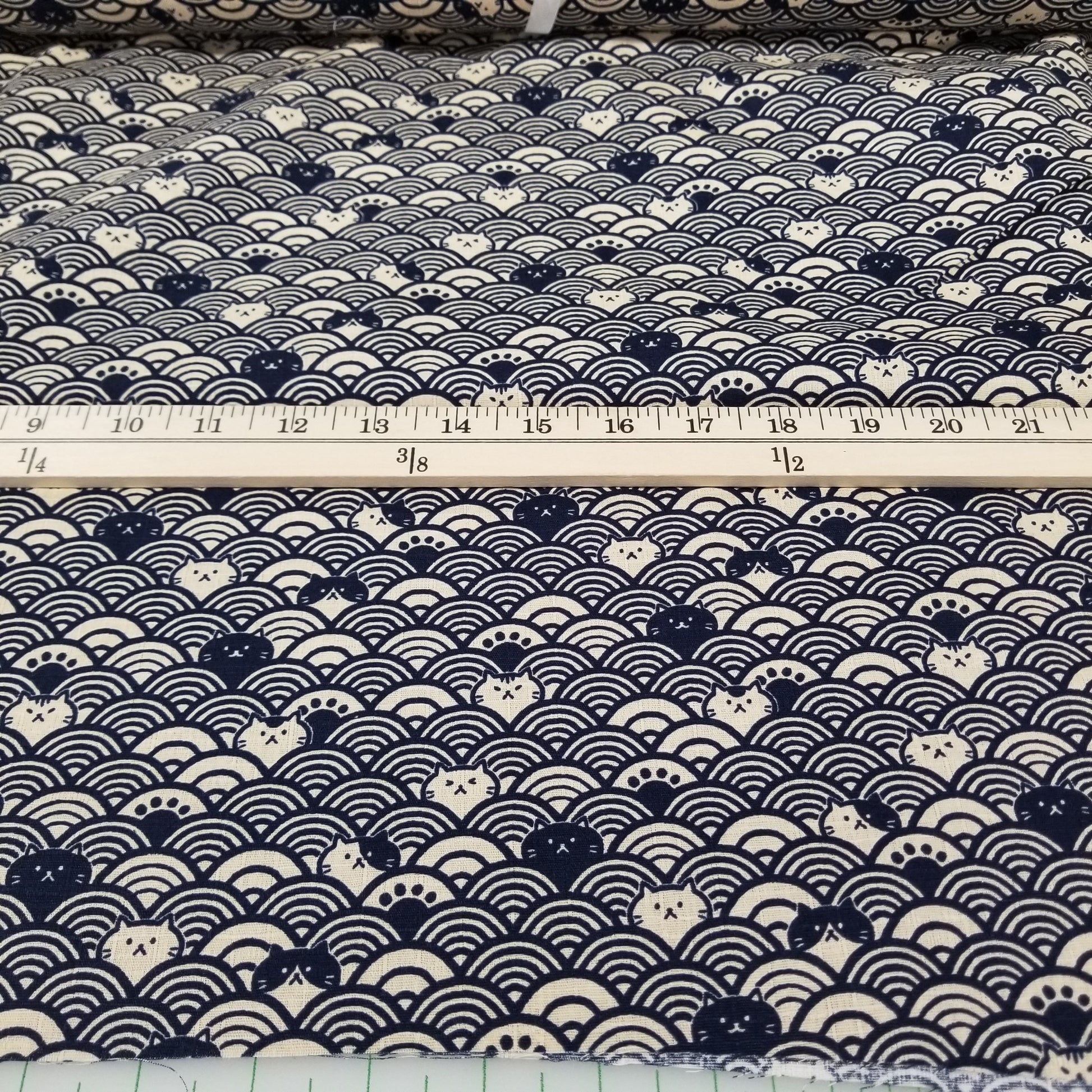 Fabric with a blue and white patterned design, measured by a tape measure.