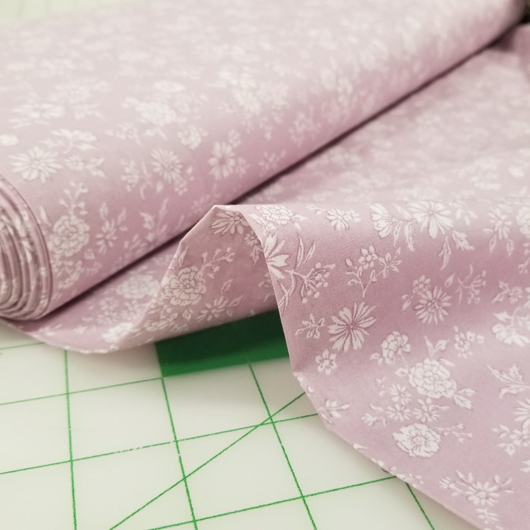 Pink floral fabric on a green cutting mat