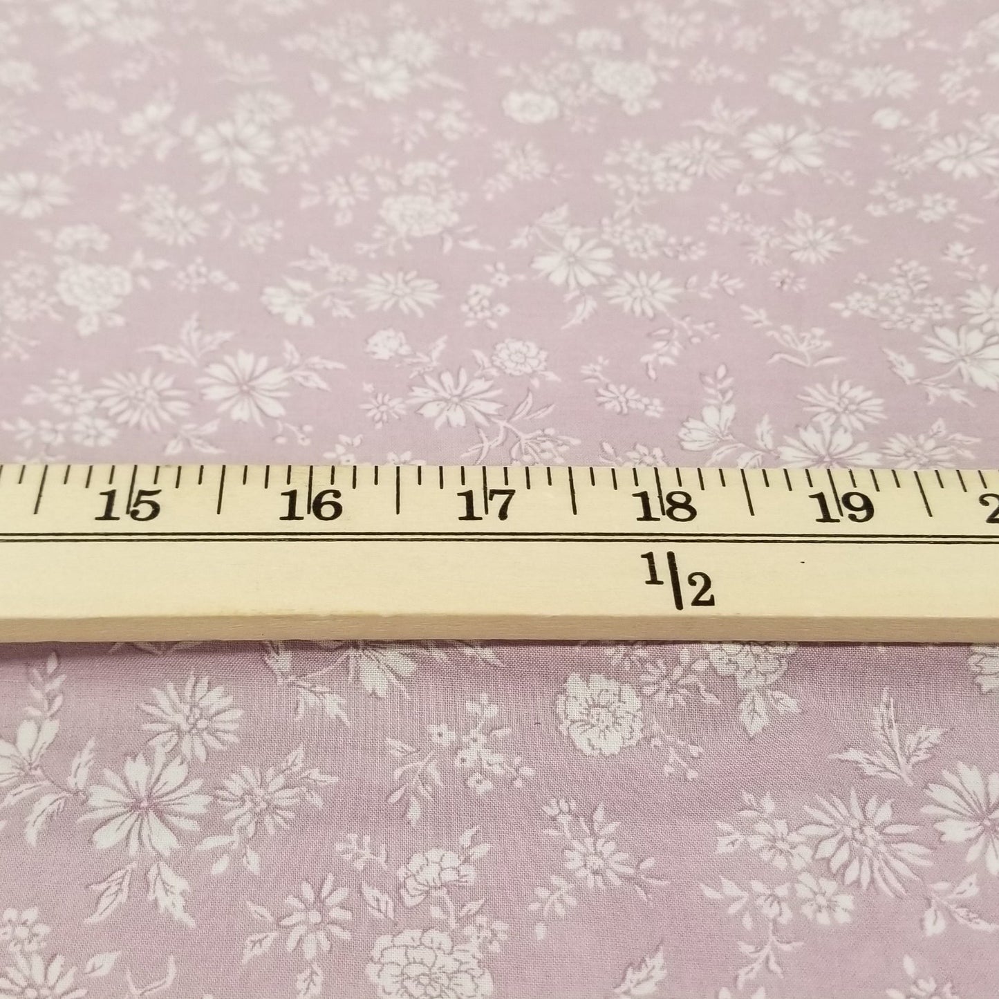 Floral-patterned fabric with a ruler for scale on a pink background