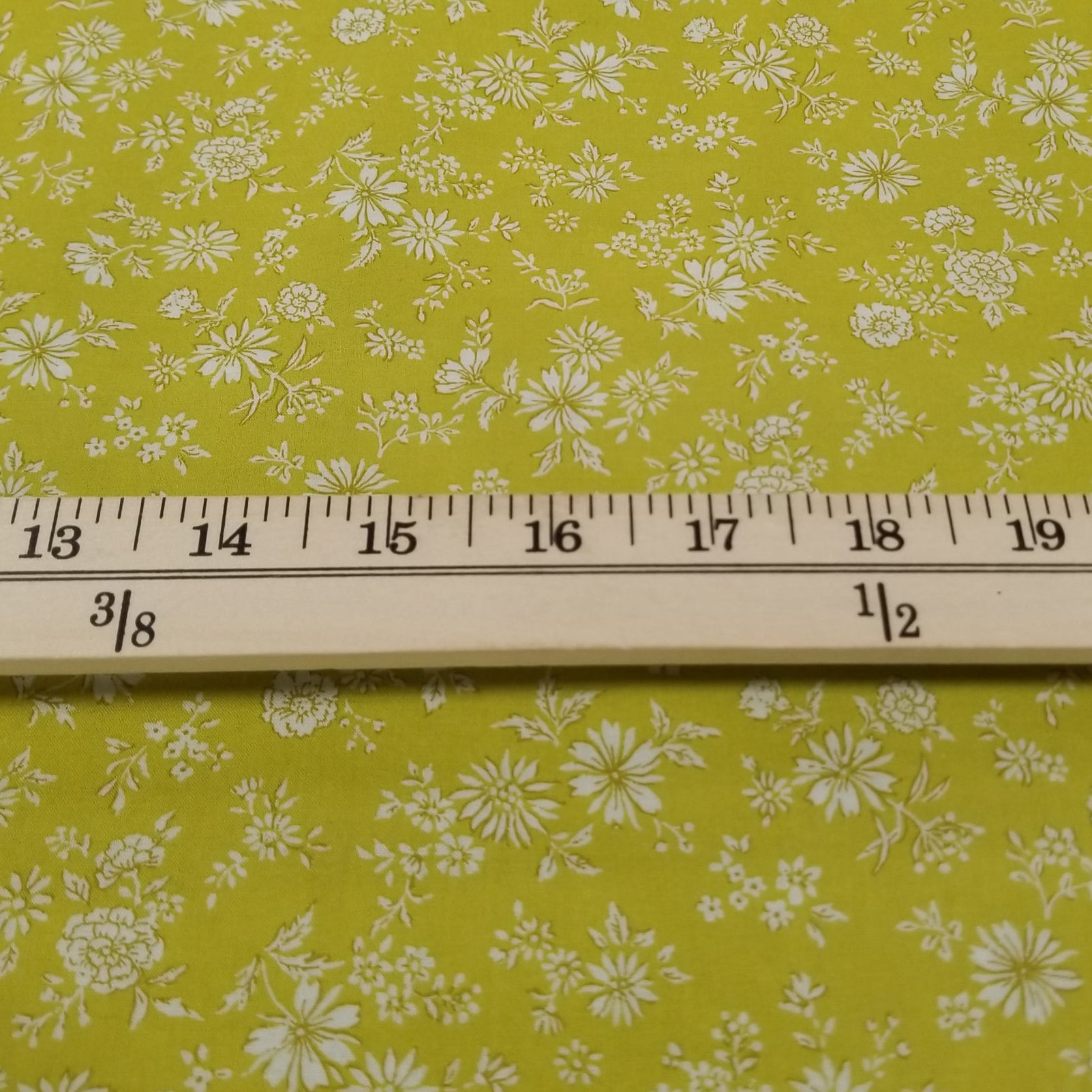 Floral-patterned fabric with a ruler for scale on a green background