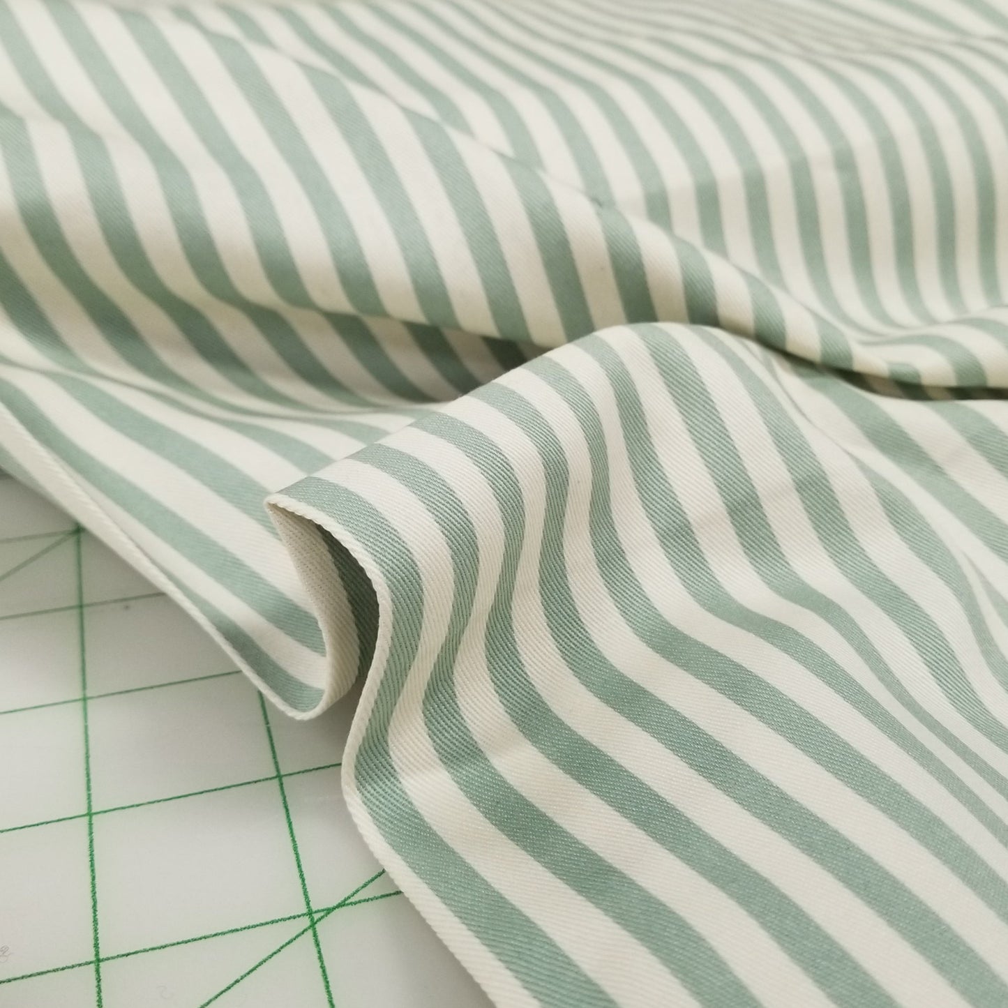 Close-up of green and white striped fabric on a cutting mat