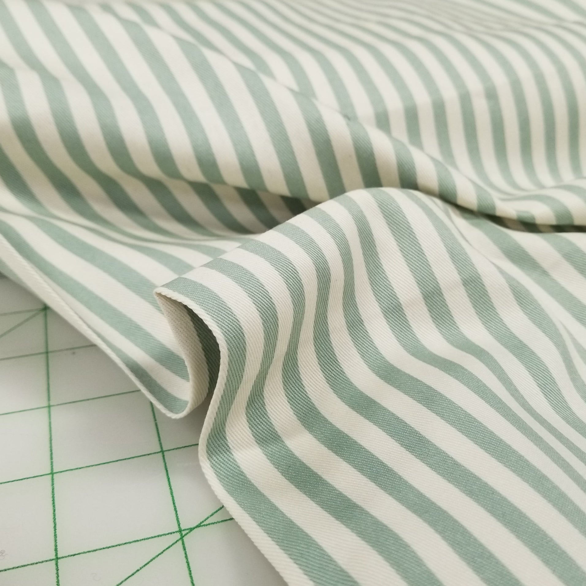 Close-up of green and white striped fabric on a cutting mat