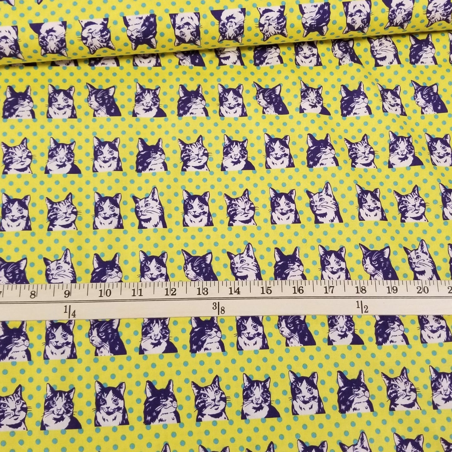 Fabric with dog pattern on a green background, measured by a ruler.