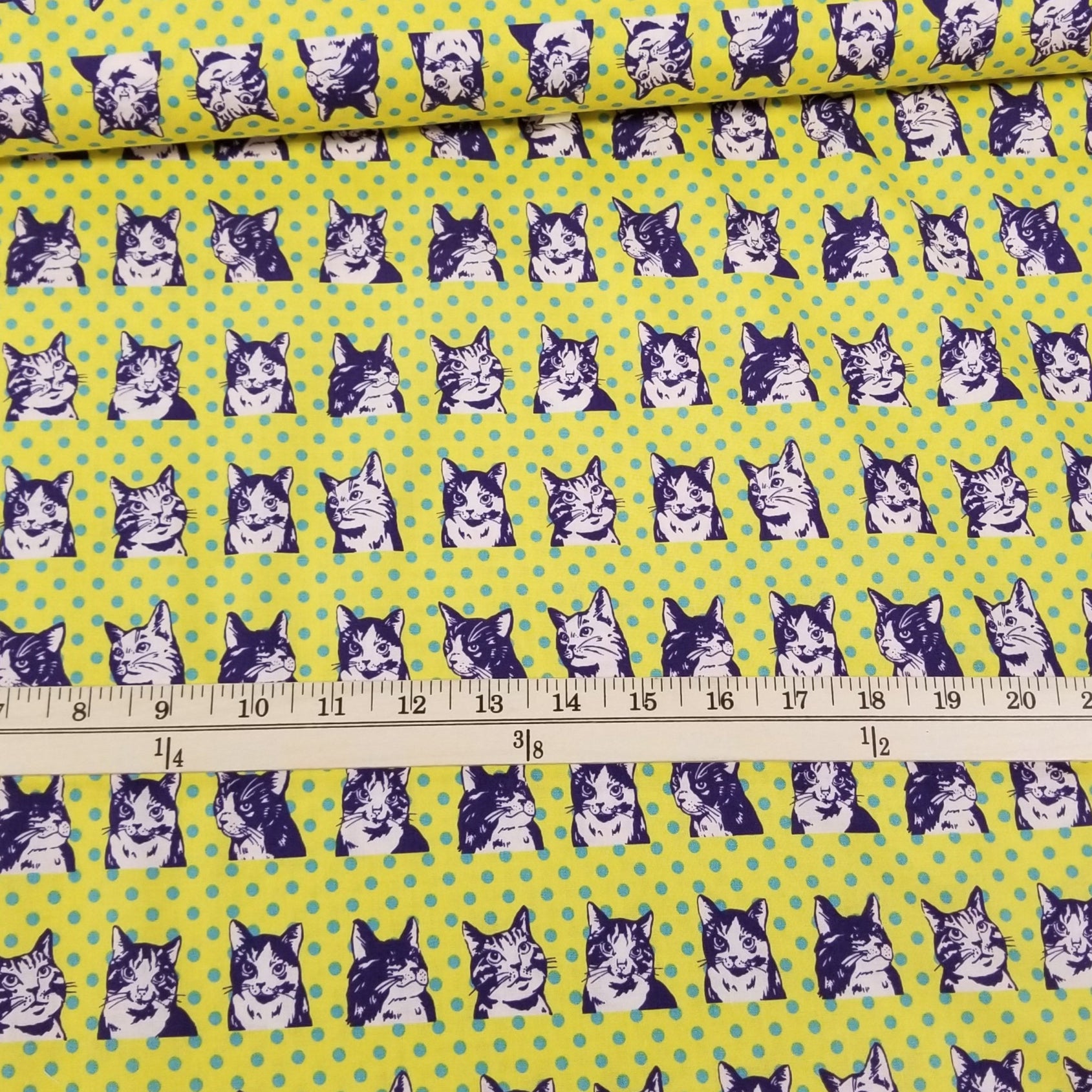 Fabric with dog pattern on a green background, measured by a ruler.