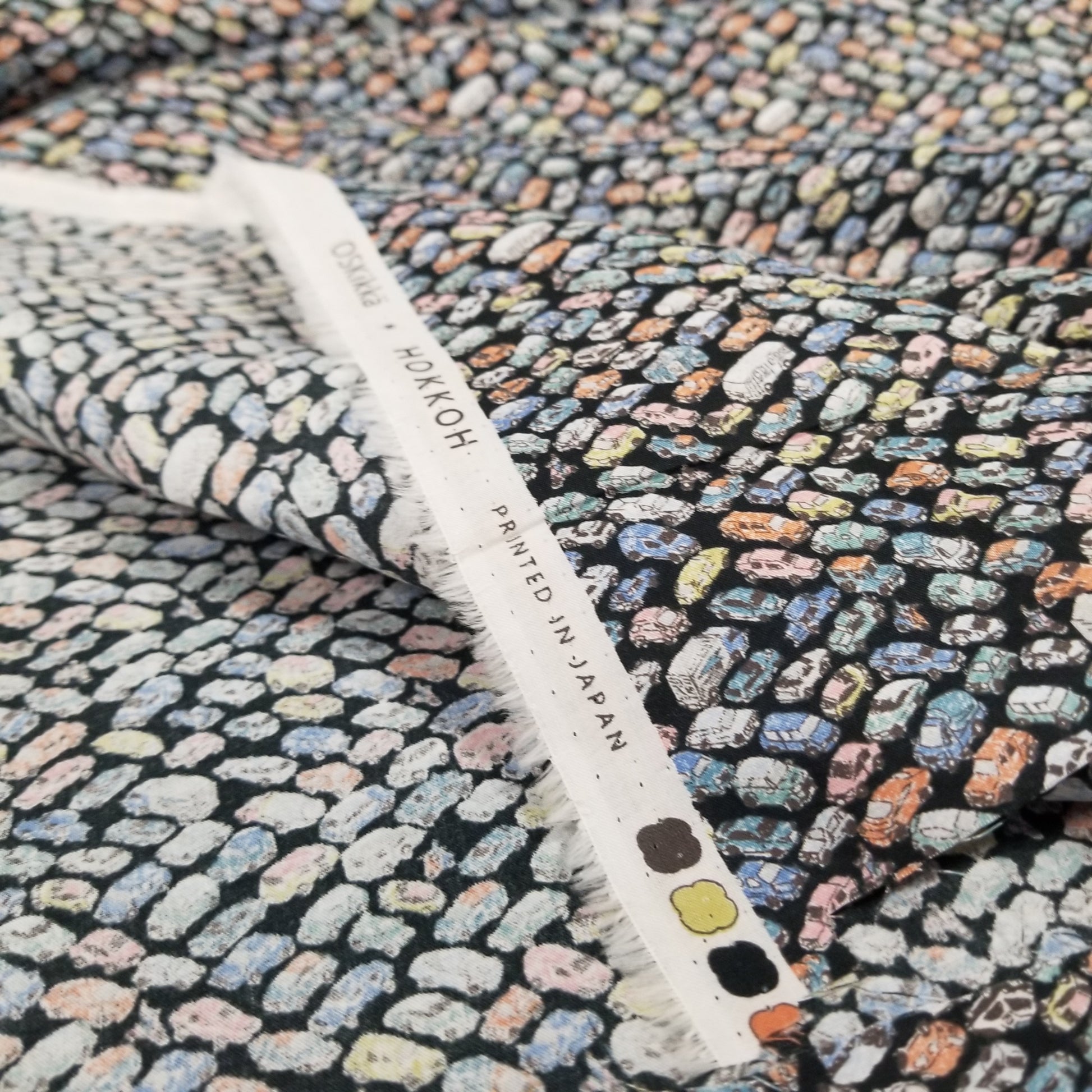 Textile with a multicolored pattern and 'Hokkoh' label on a hanger.