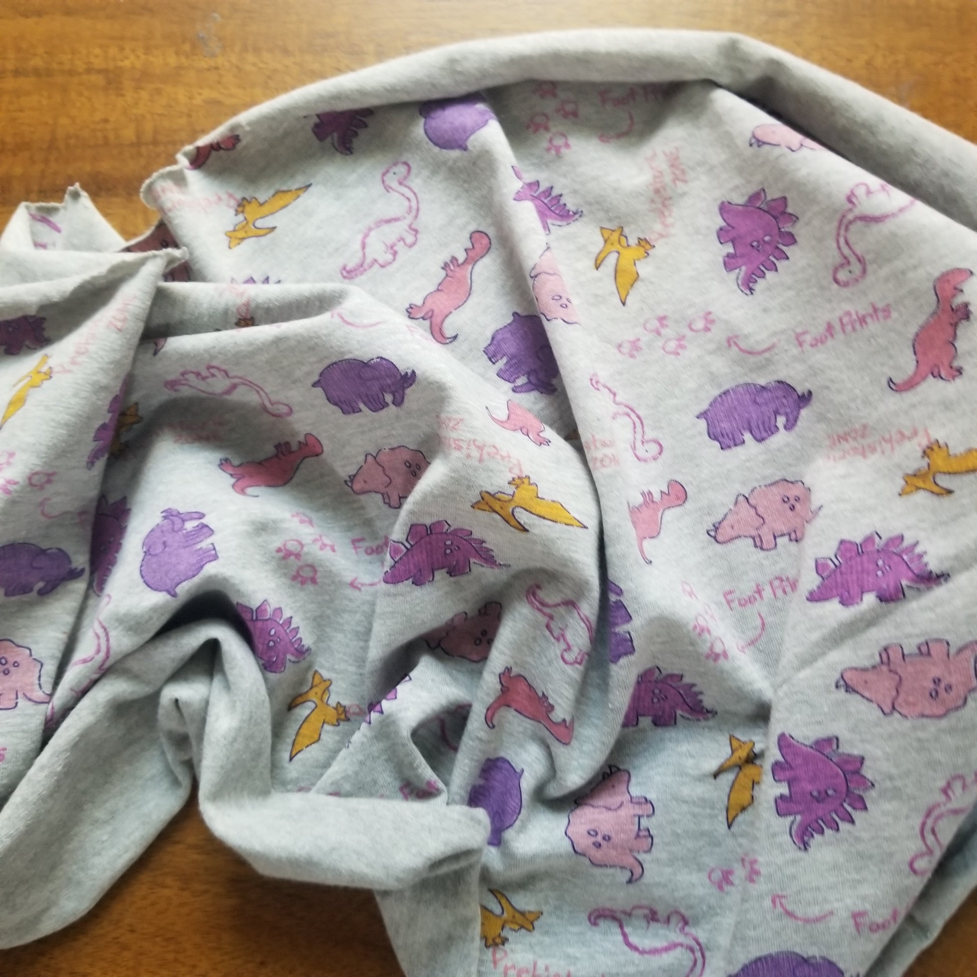 Folded fabric with colorful dinosaur pattern on a wooden surface