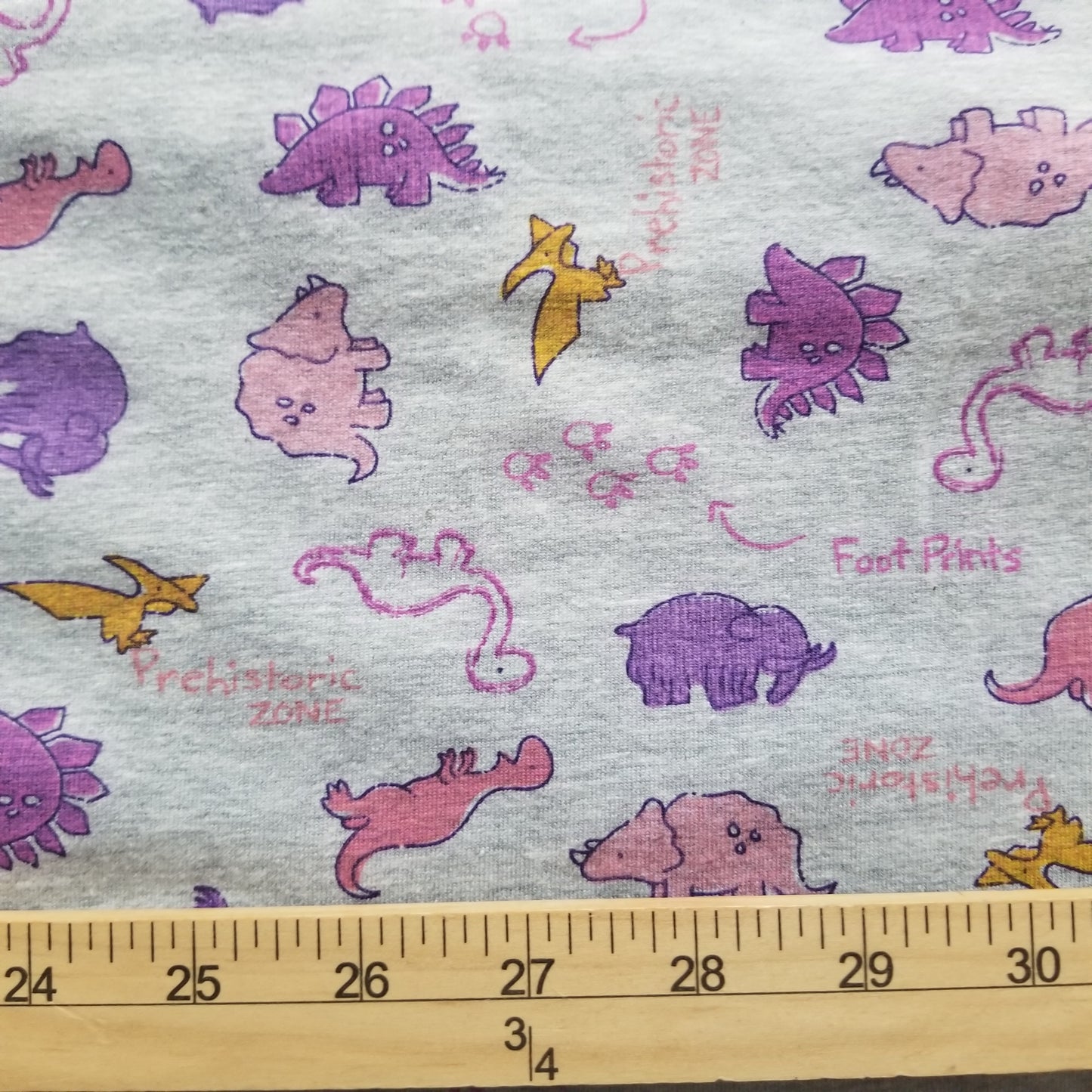 Fabric with dinosaur patterns and a ruler for scale on the right side.