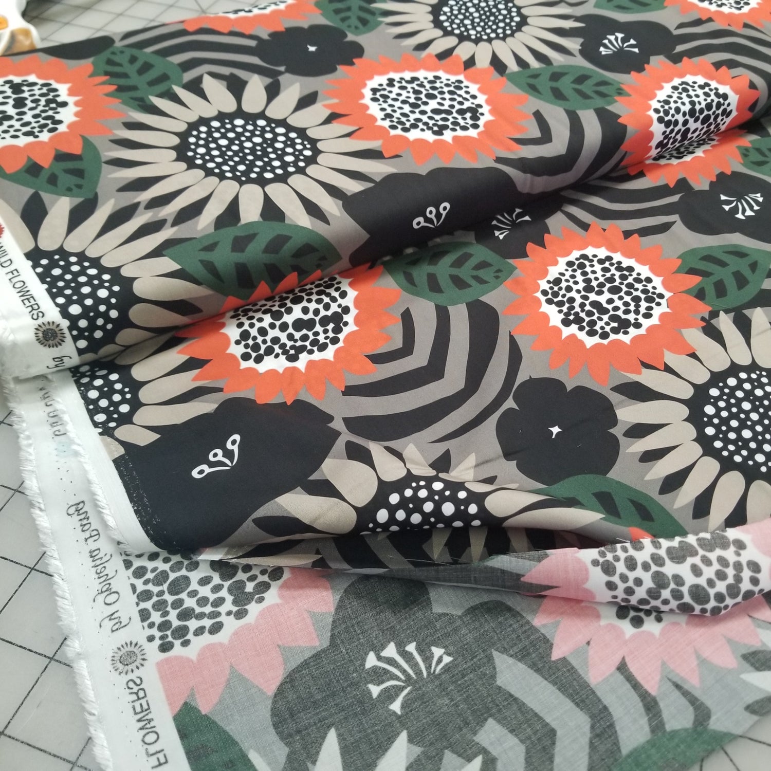 Floral fabric swatches with black, orange, and pink patterns on a grid background