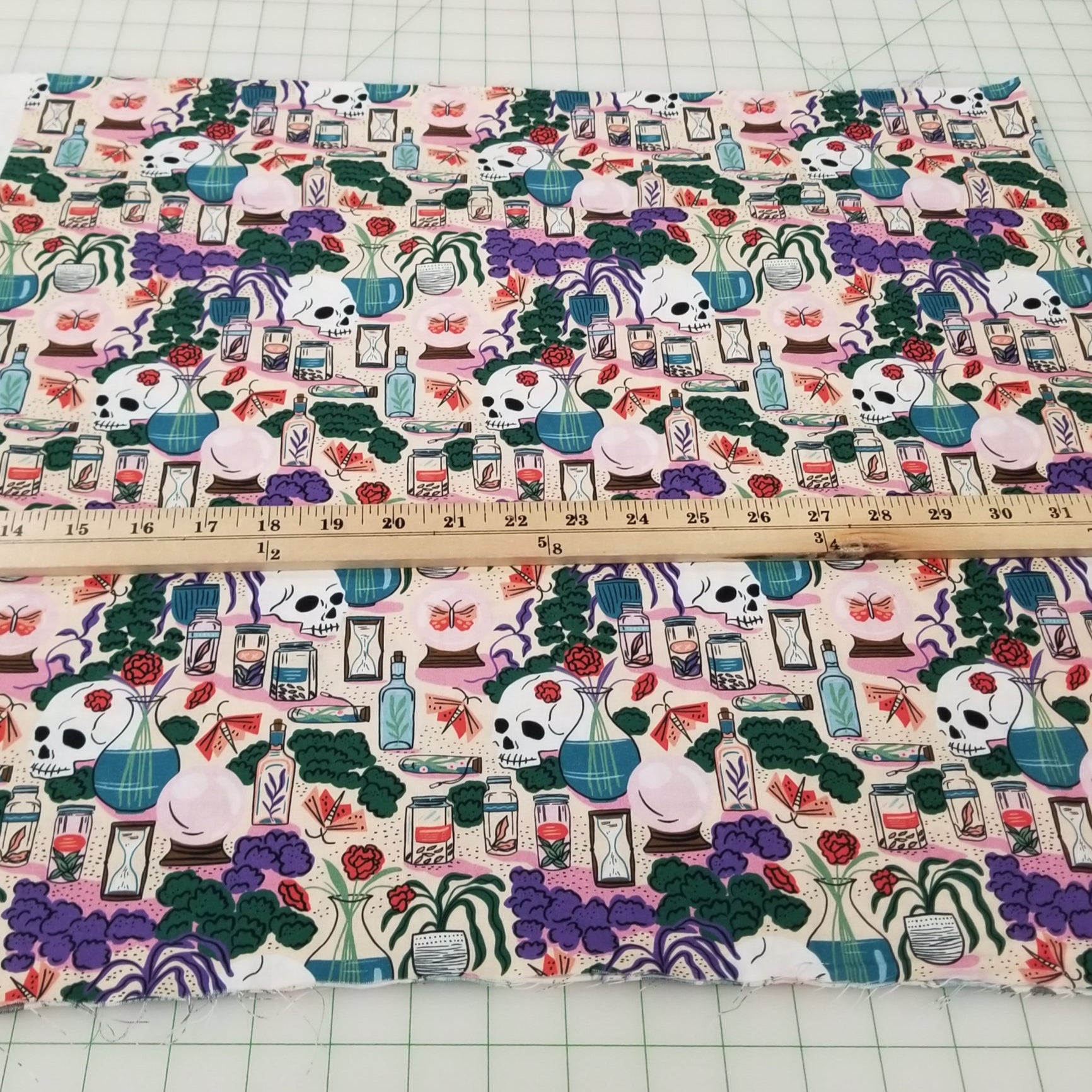 Fabric with a colorful pattern of cartoon characters and objects, measured by a ruler on a grid background.