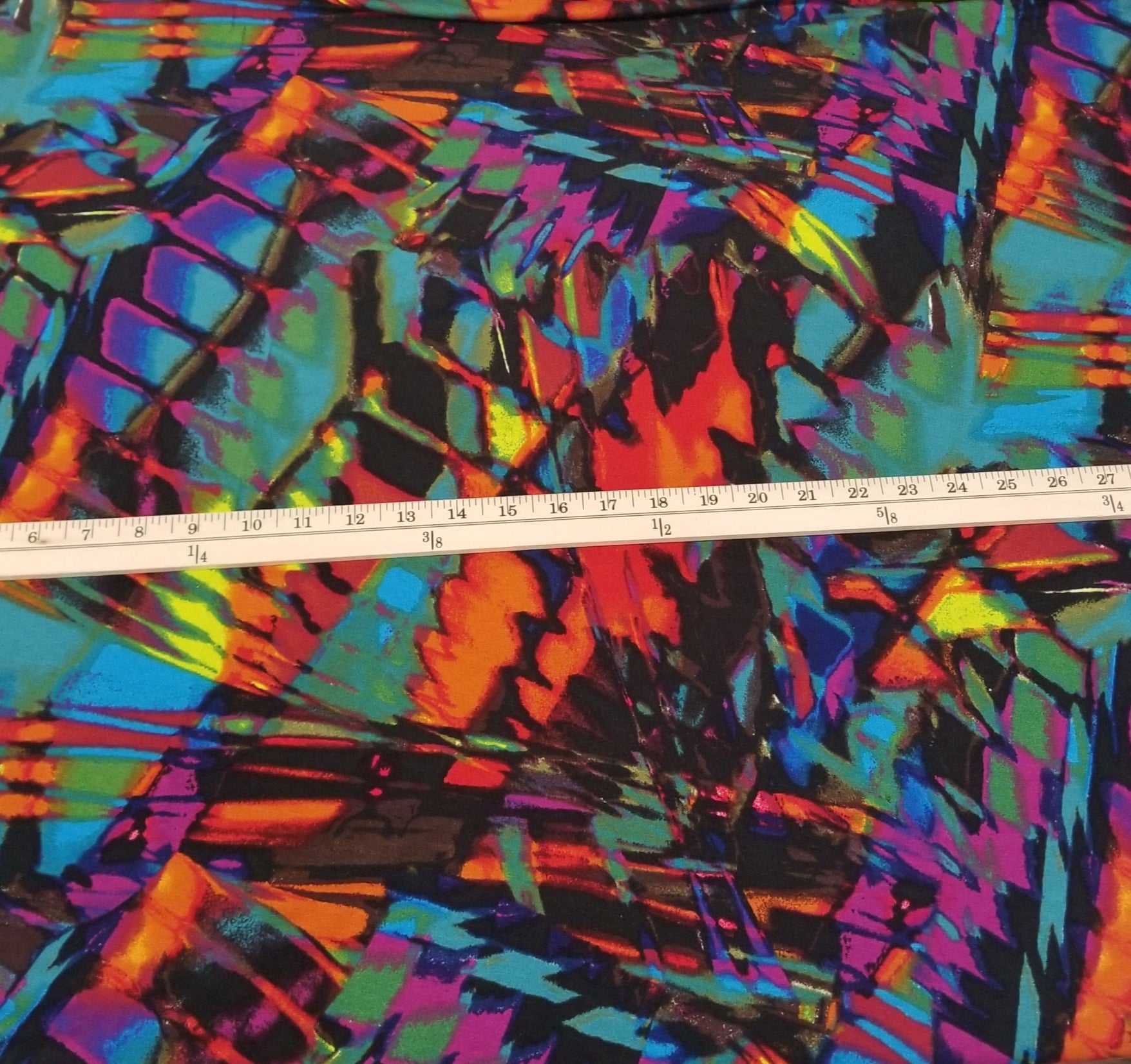 Colorful abstract patterned fabric with a ruler for scale on a neutral background