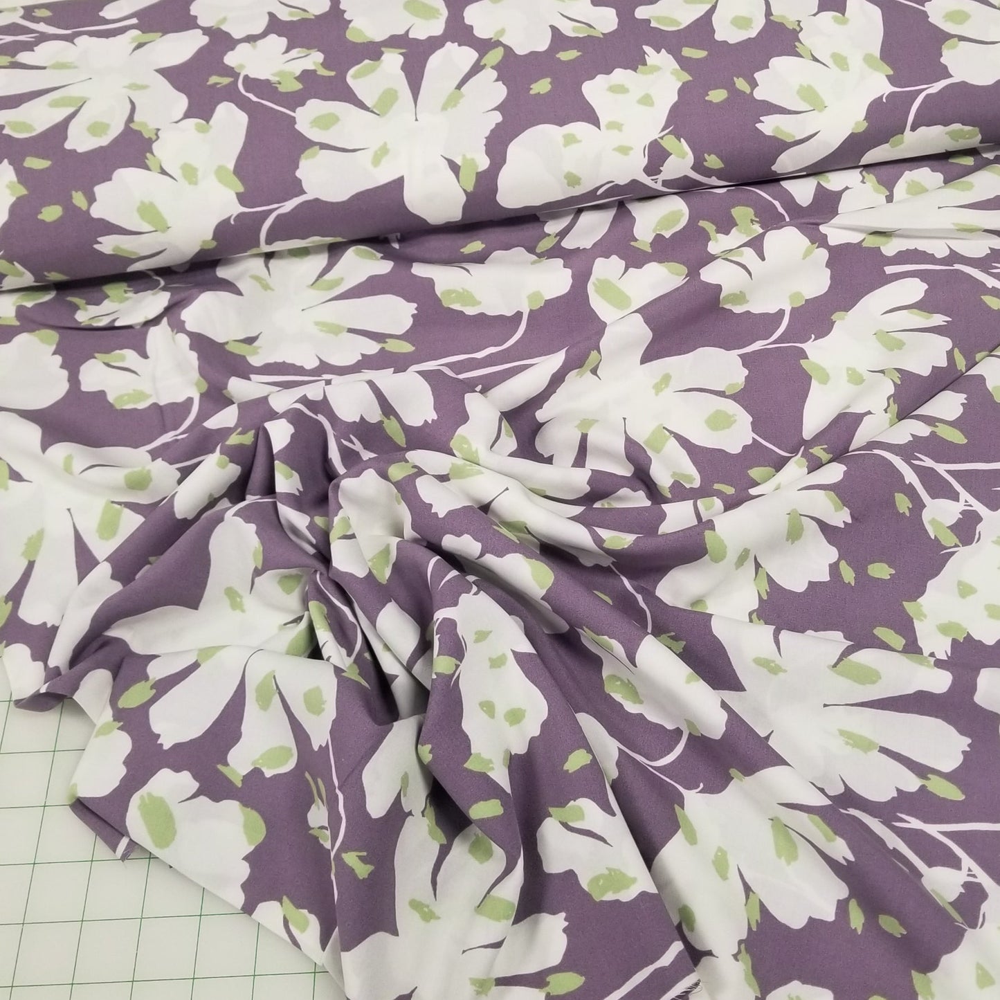 Floral fabric with white flowers on a purple background on a grid surface