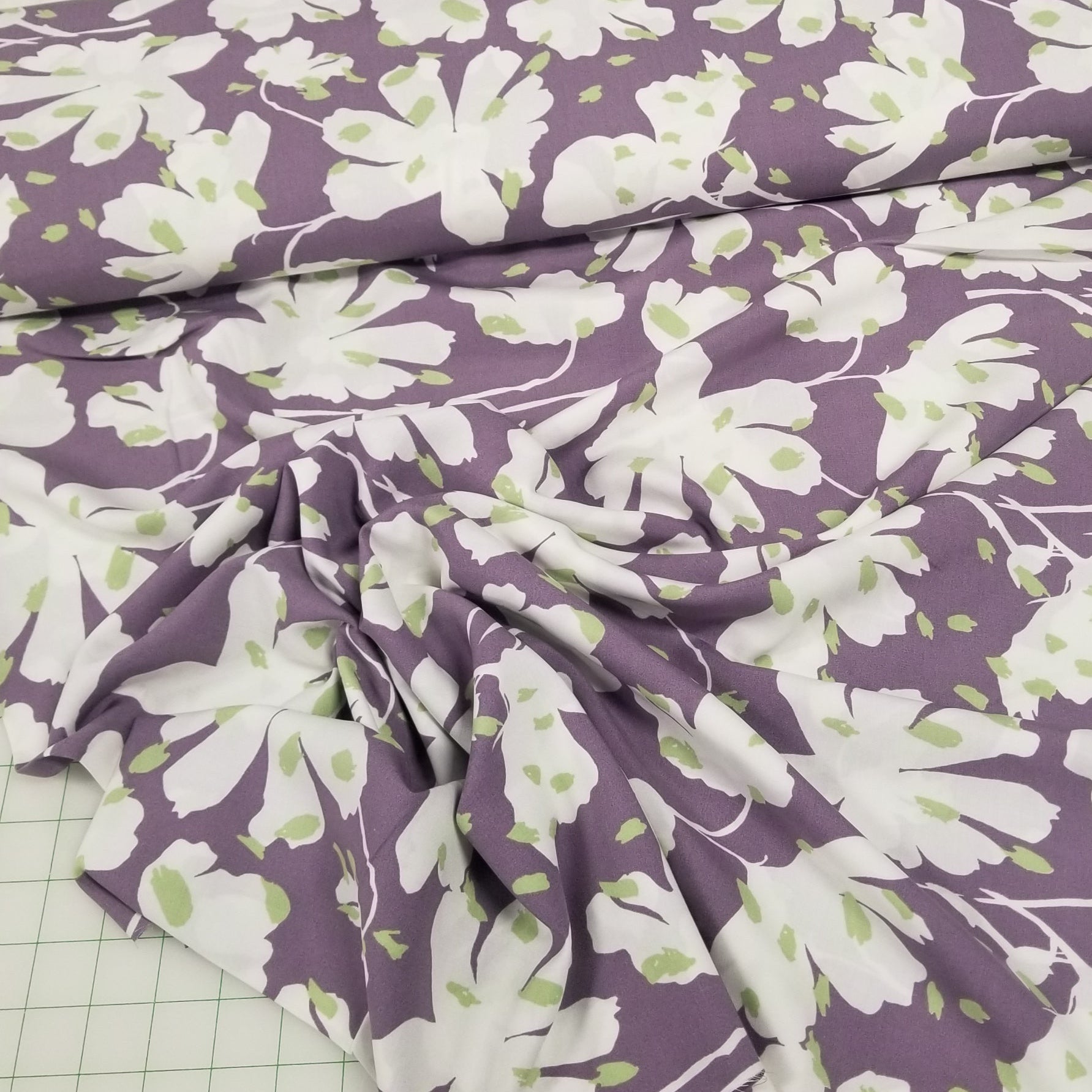 Floral fabric with white flowers on a purple background on a grid surface