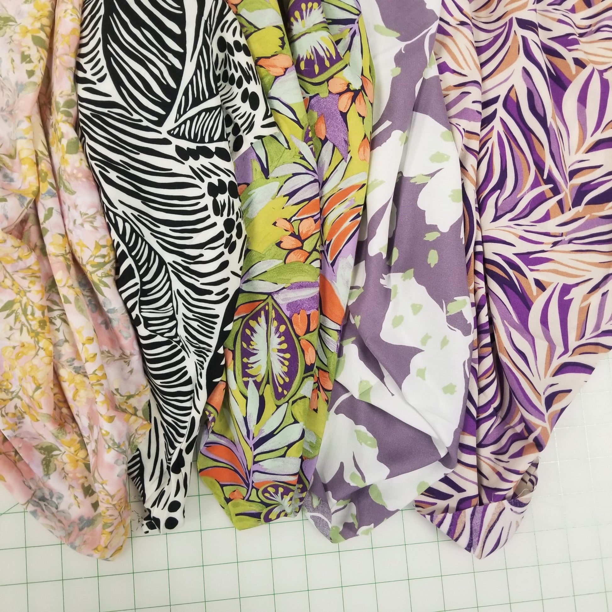 Stack of colorful patterned fabrics on a grid surface