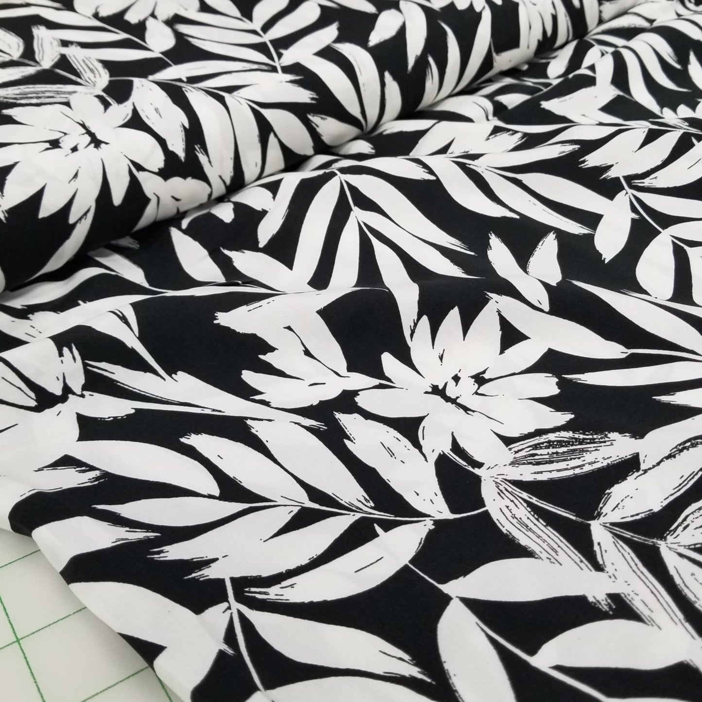Black fabric with white leaf pattern on a cutting mat