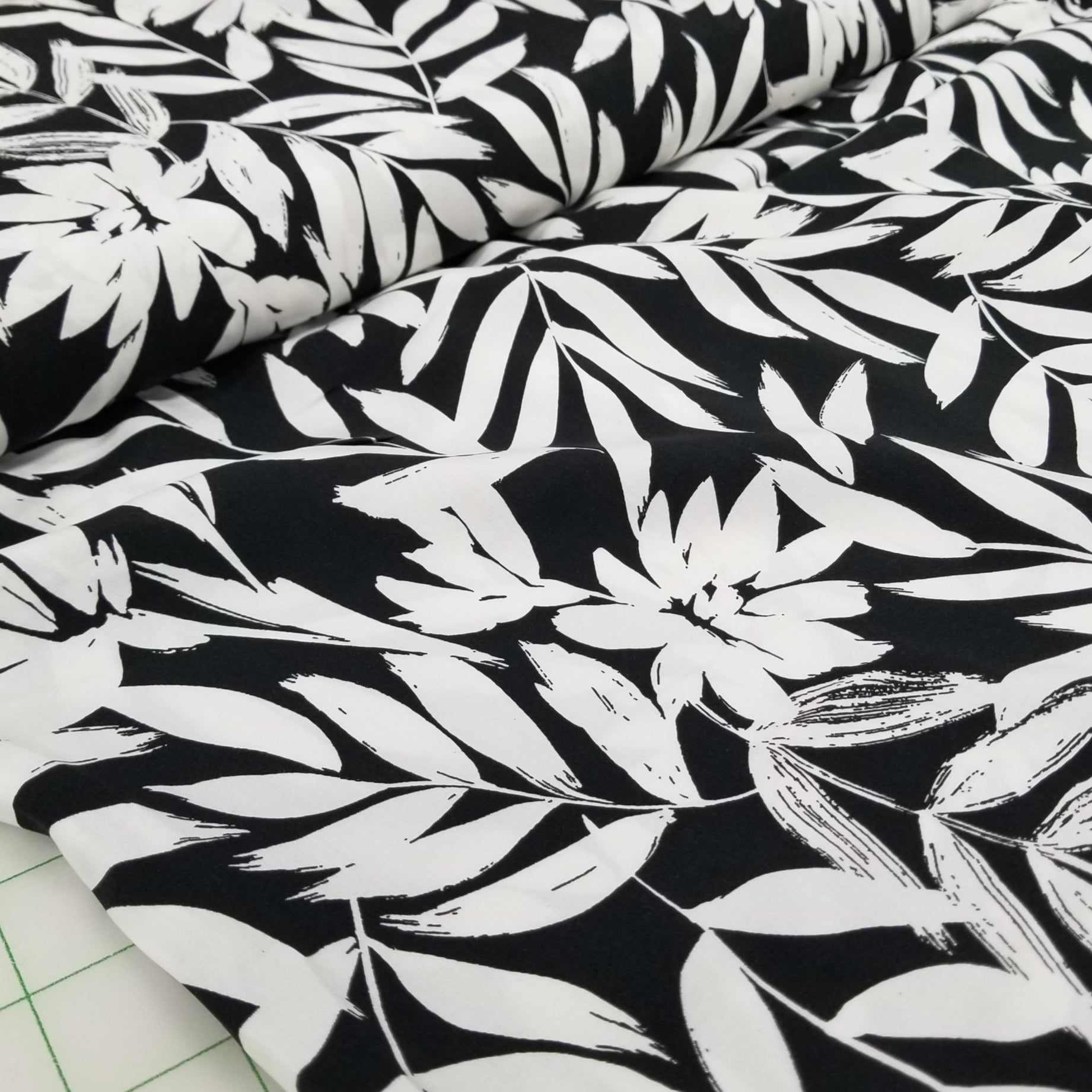 Black fabric with white leaf pattern on a cutting mat