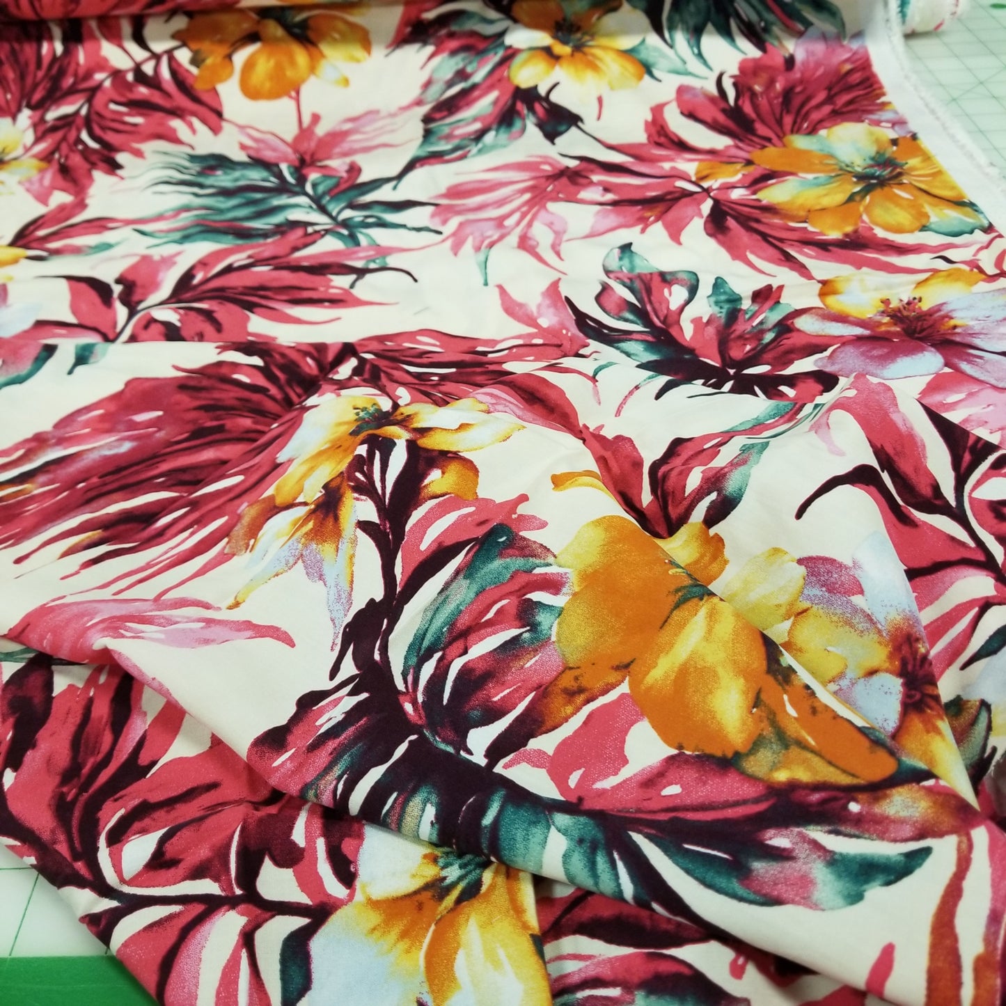 Close-up of a colorful floral fabric with pink, yellow, and green flowers.