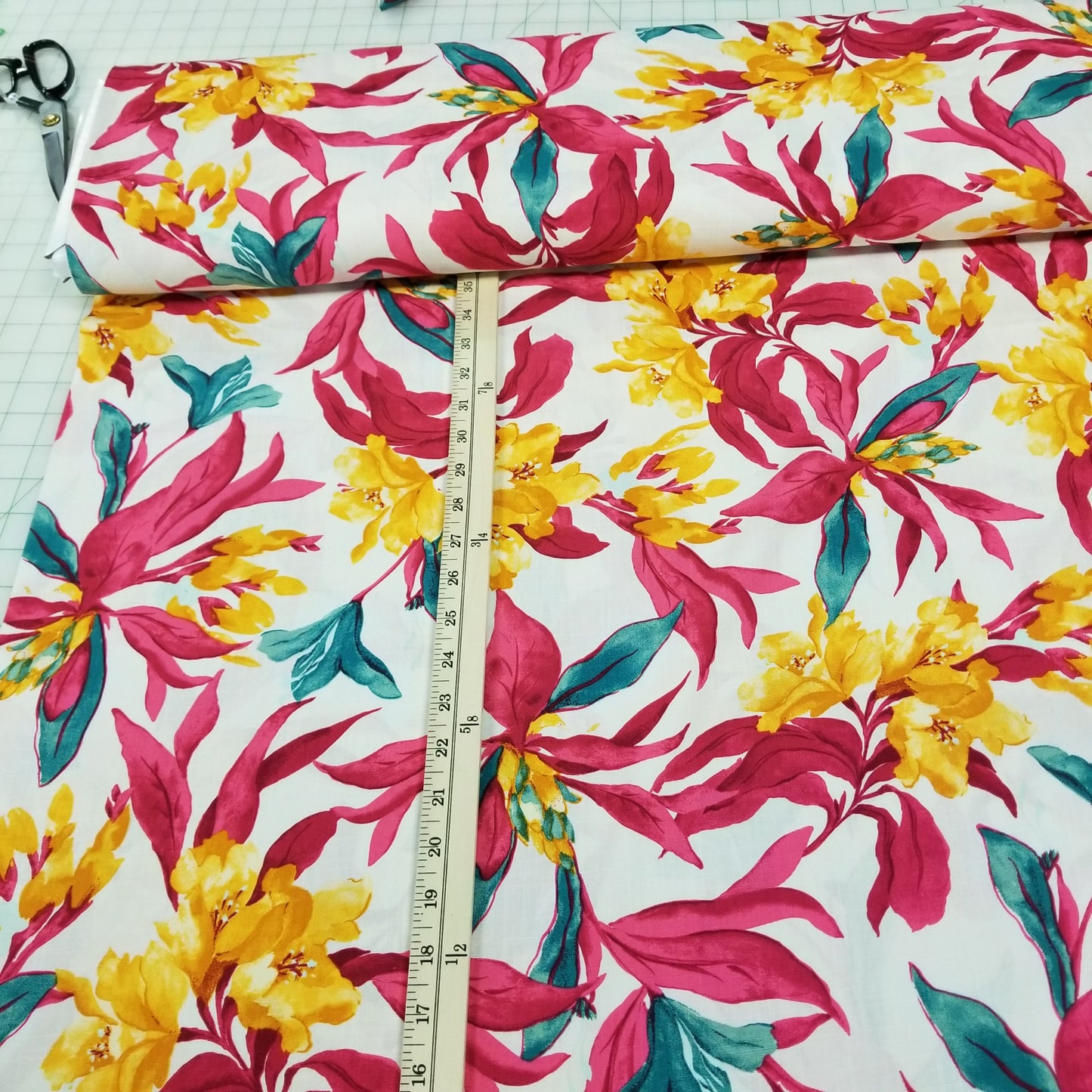 Floral fabric with pink, yellow, and green flowers on a white background, measured with a ruler.