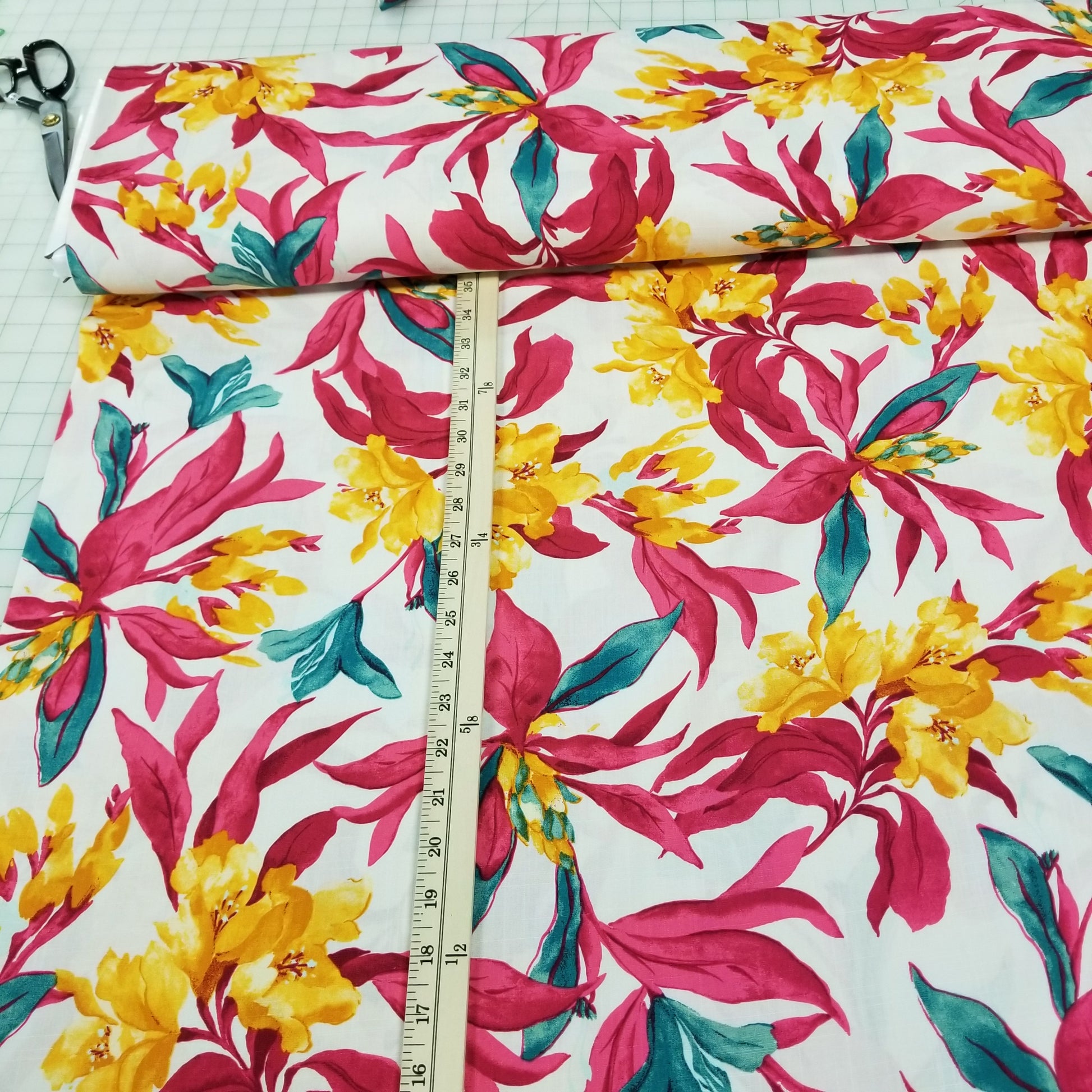 Floral fabric with pink, yellow, and green flowers on a white background, measured with a ruler.