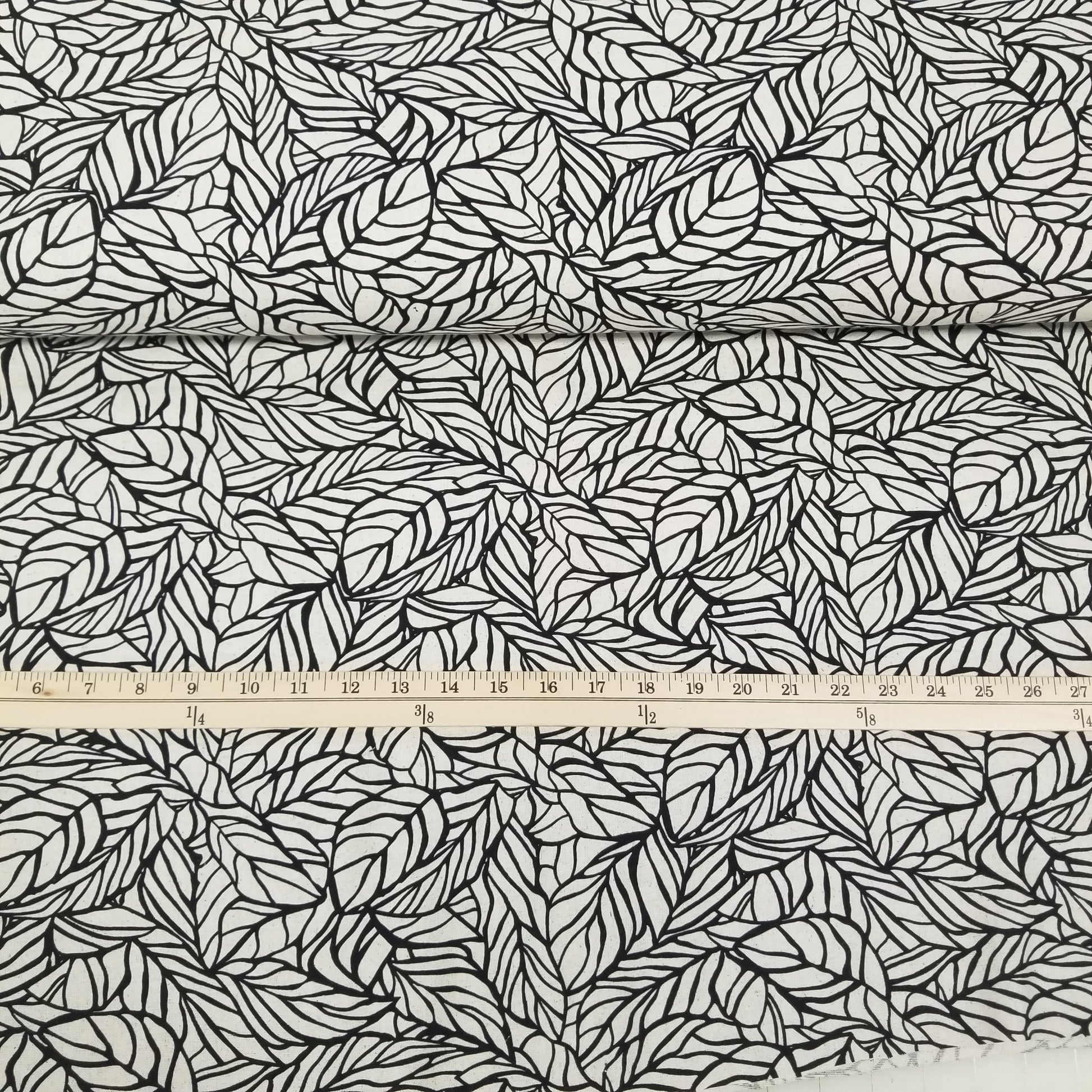 Fabric with black leaf pattern and a ruler for scale