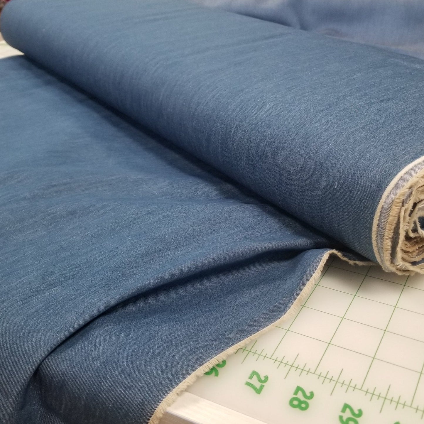 Roll of blue fabric with a grid ruler in a store setting
