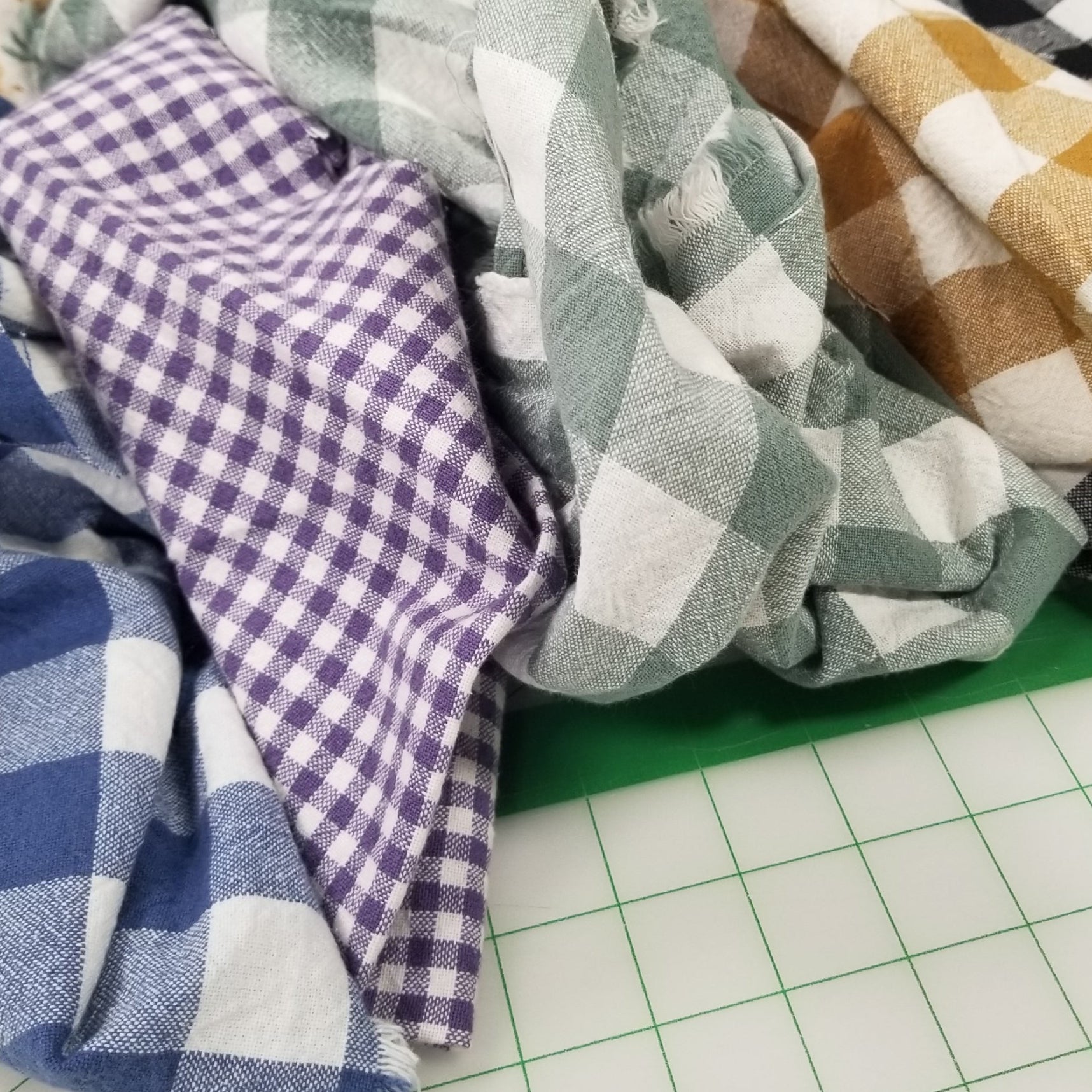 Stack of folded fabric swatches in various patterns and colors on a grid background