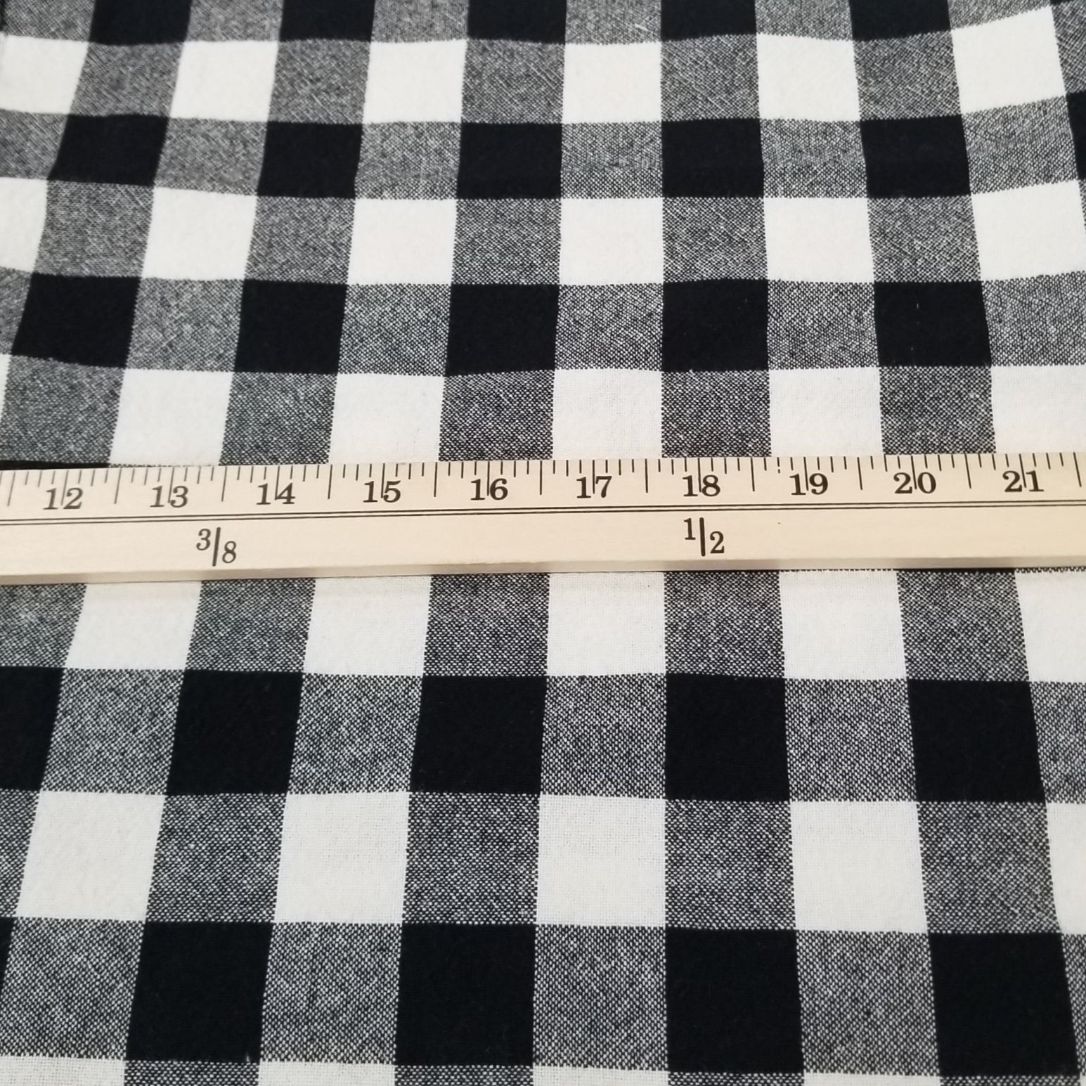 Black and white checkered fabric with a ruler on a grid background