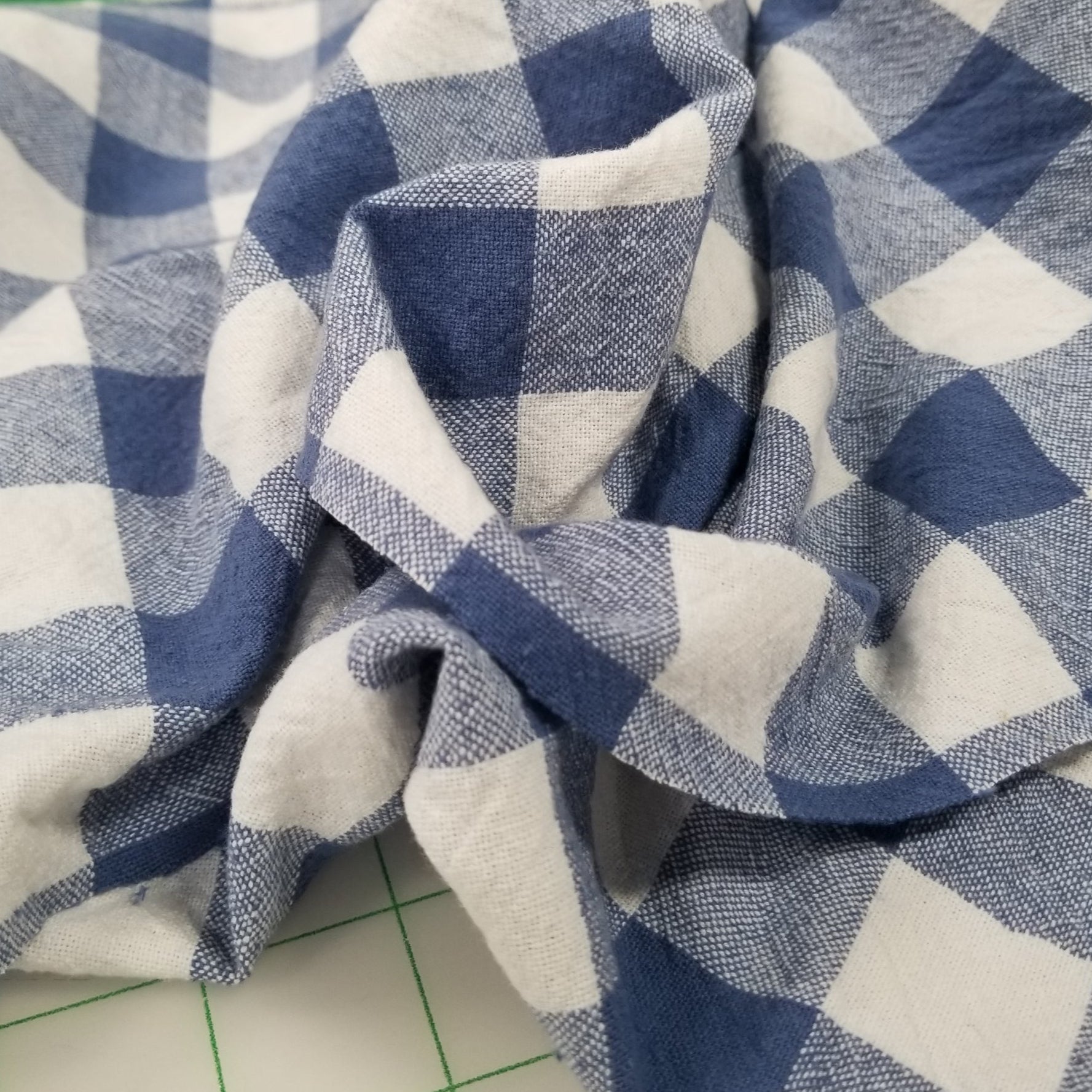 Blue and white checkered fabric on a green cutting mat