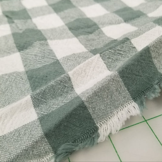 Plaid fabric with green and white pattern on a grid background. organic cotton checkered woven