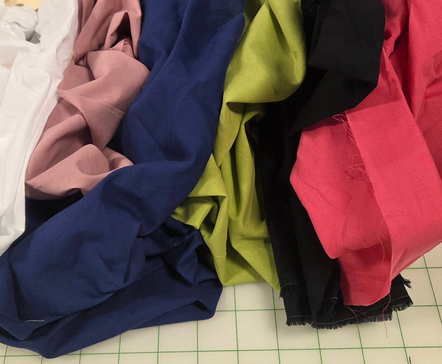 Colorful fabric samples on a grid-patterned surface with tools and materials around.