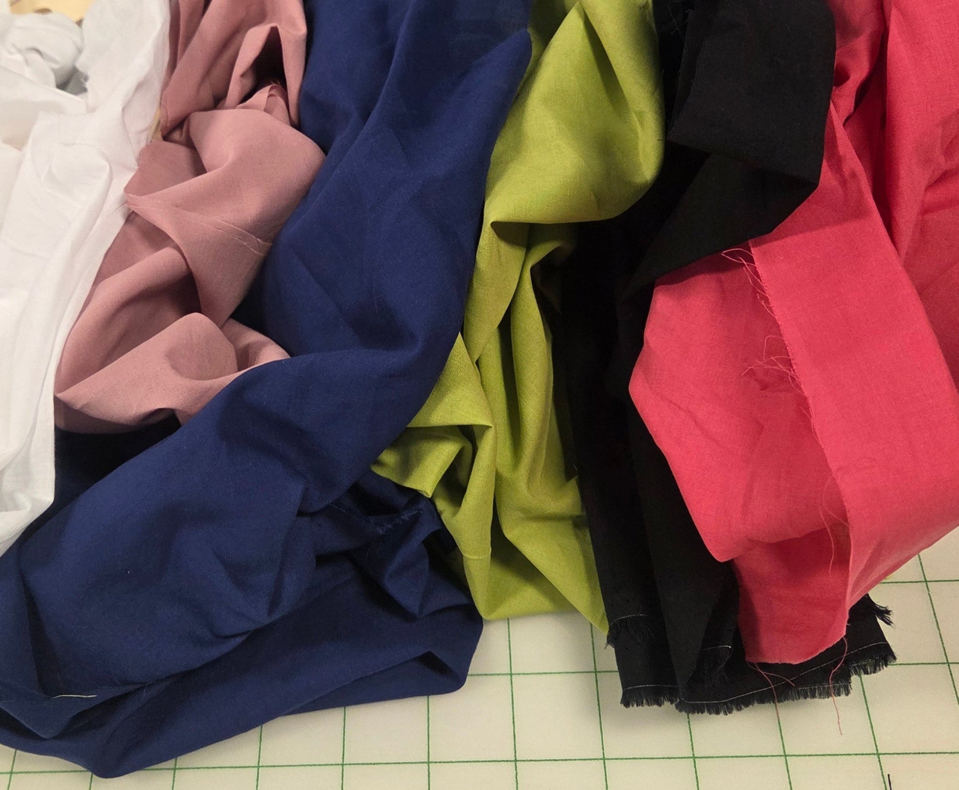 Colorful fabric samples on a grid-patterned surface with tools and materials around.