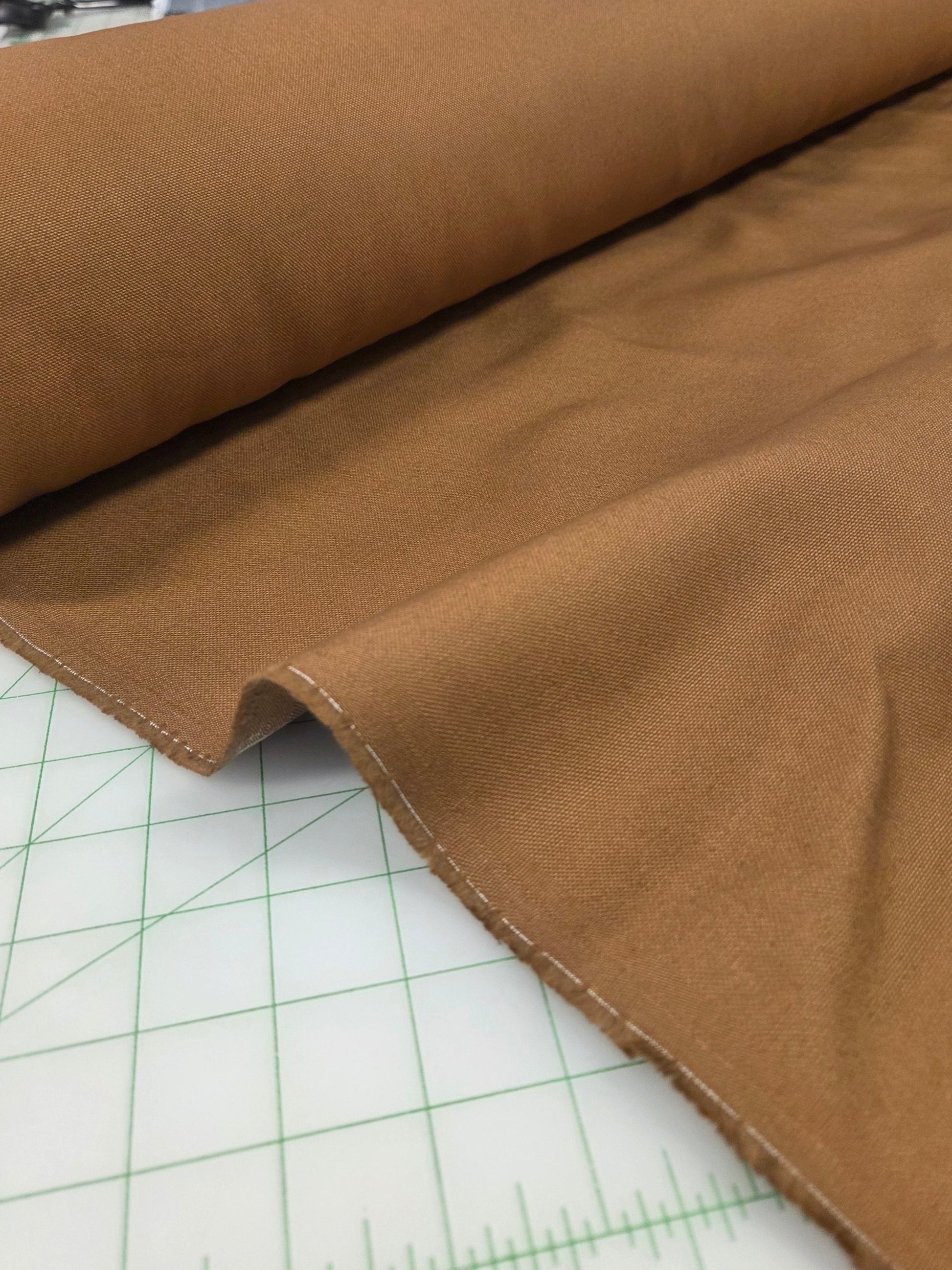 Brown fabric on a cutting mat with grid lines. cotton canvas