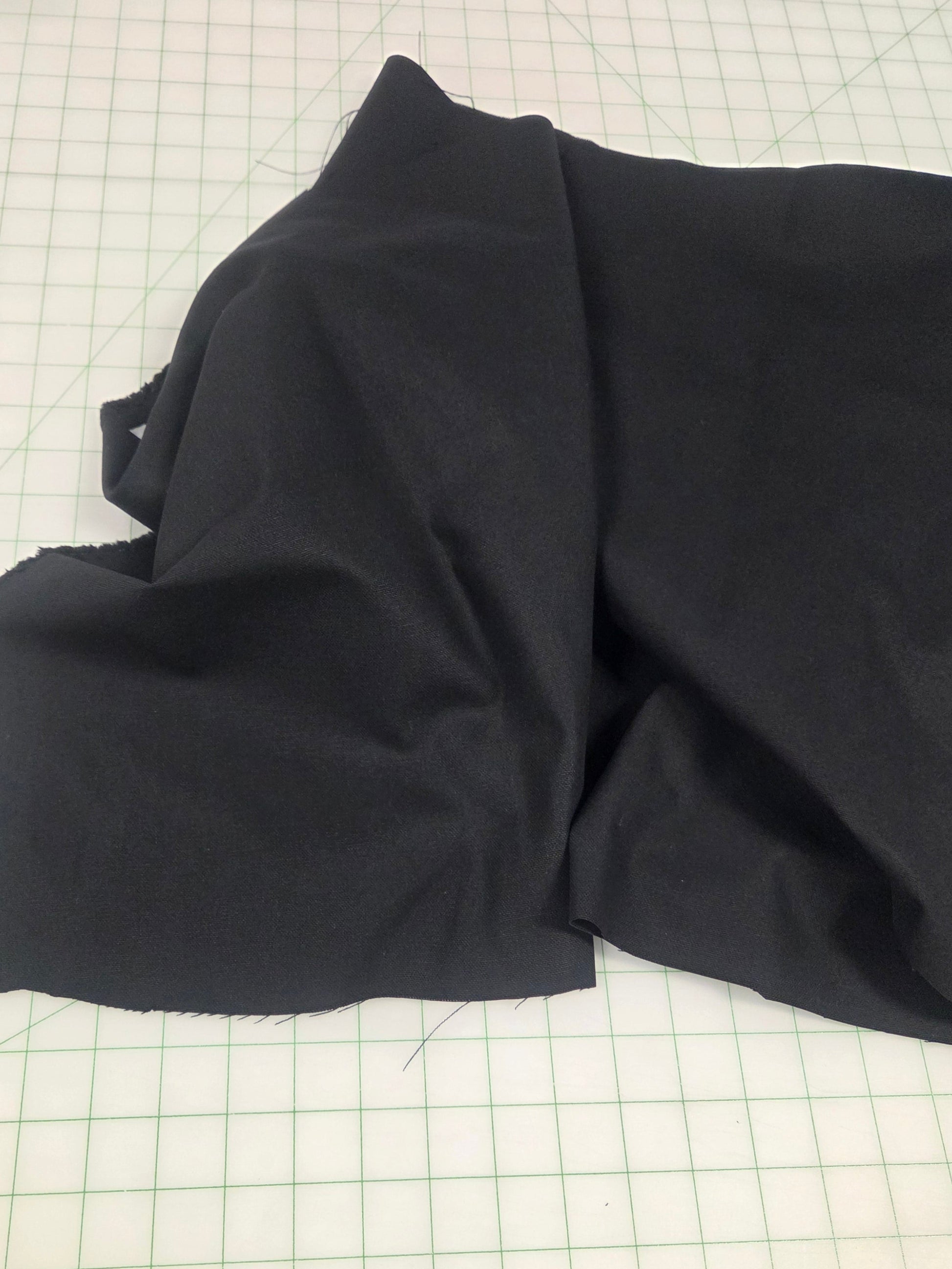 Folded black fabric on a grid surface, black canvas fabric sold by the yard