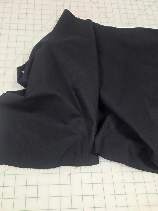 Folded black fabric on a grid surface, black canvas fabric sold by the yard