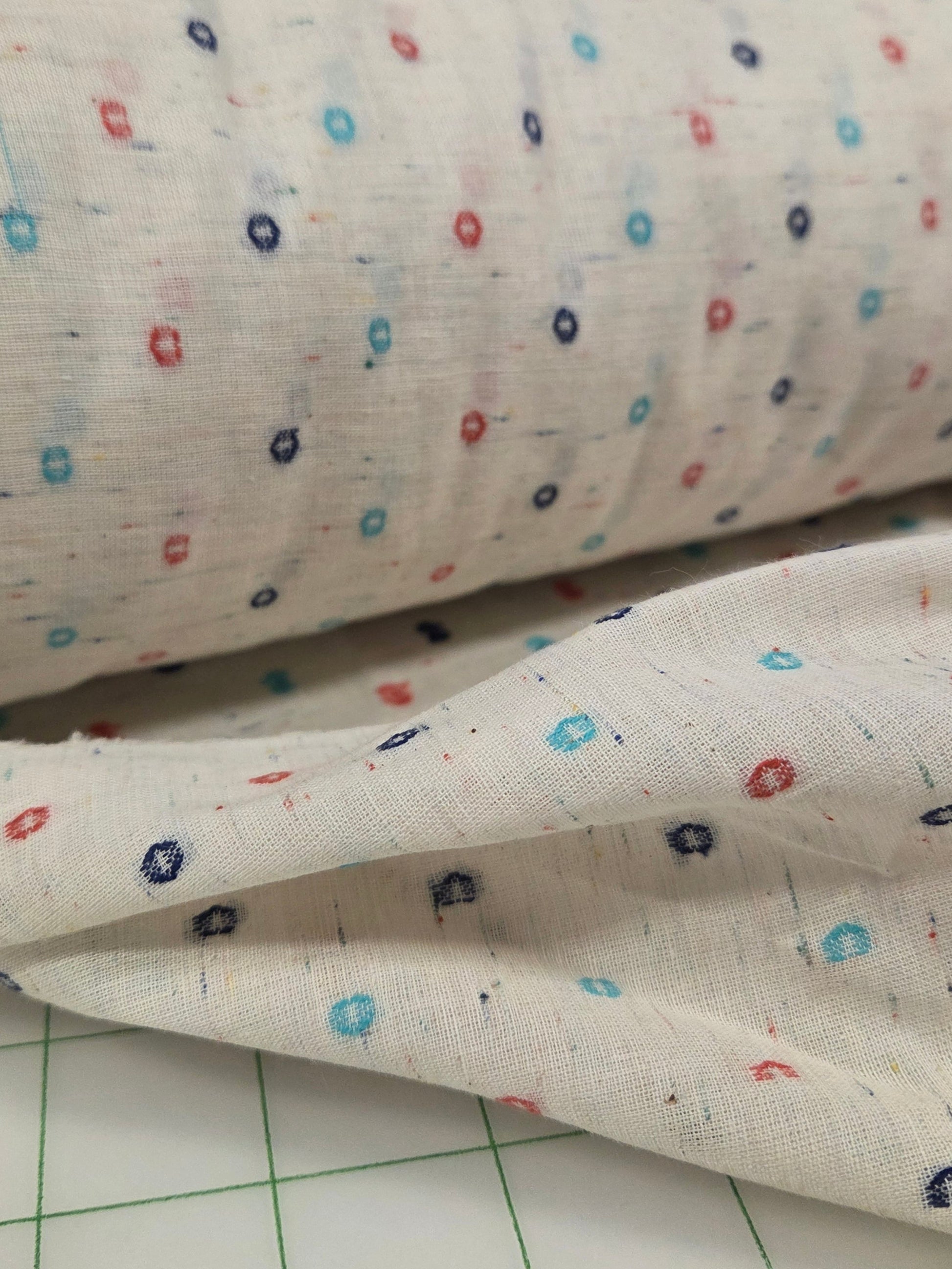 Close-up of fabric with small colorful patterns on a grid background