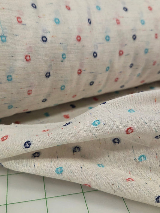 Close-up of fabric with small colorful patterns on a grid background
