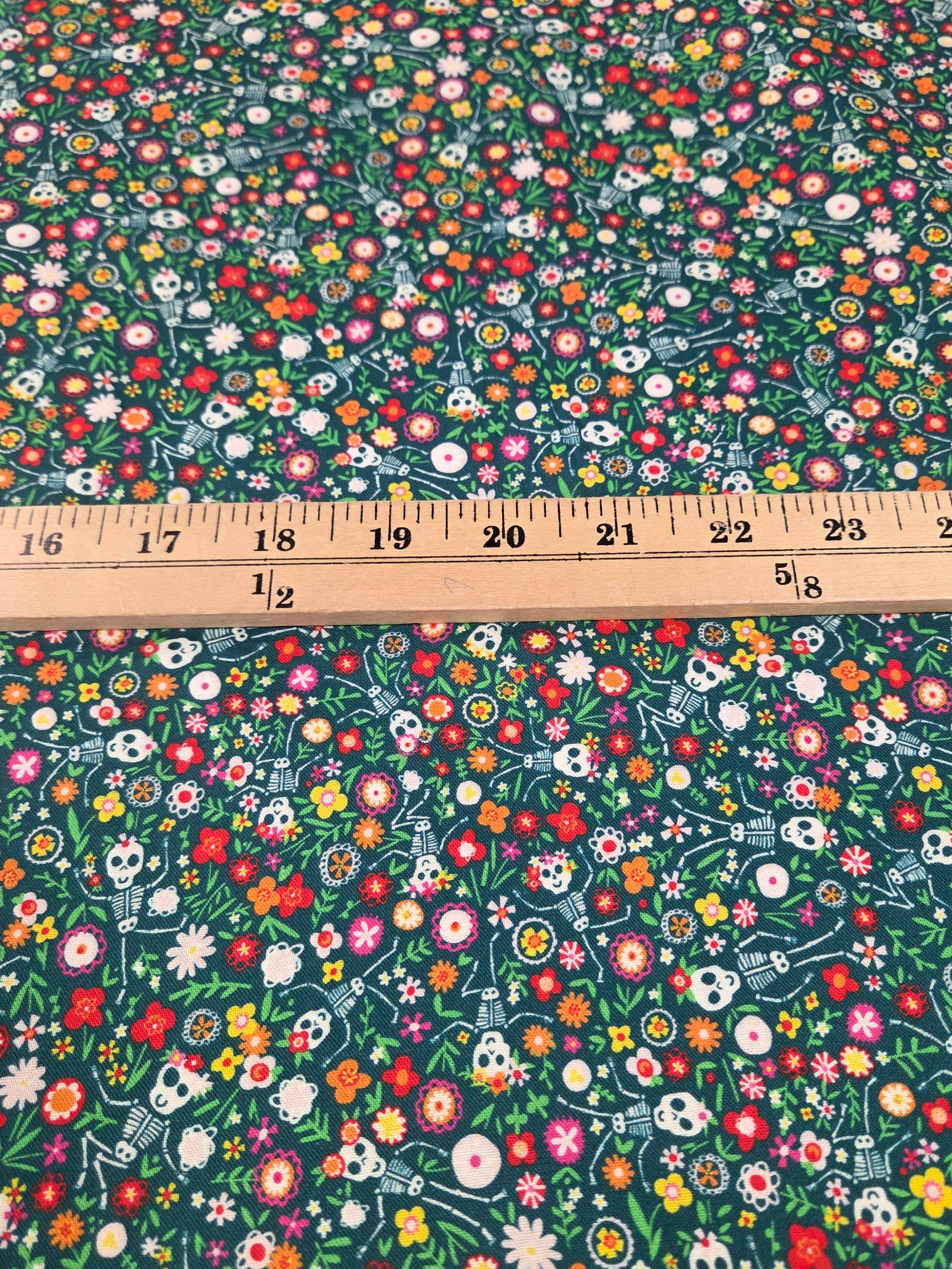 Fabric with colorful skull and floral pattern and a ruler for scale.