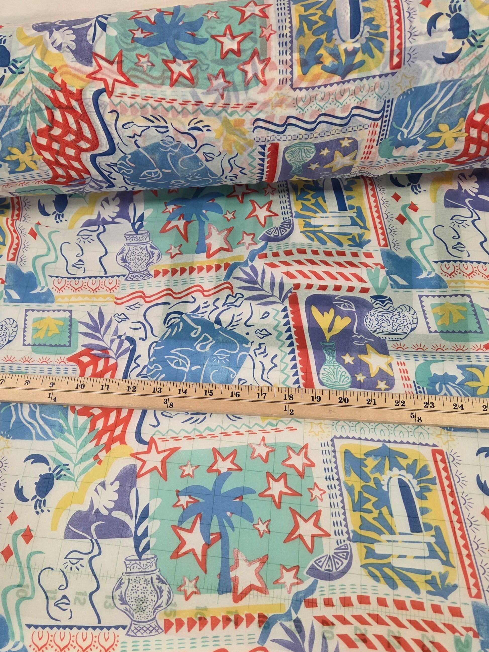 Colorful fabric with animal patterns and a ruler for scale on a neutral background