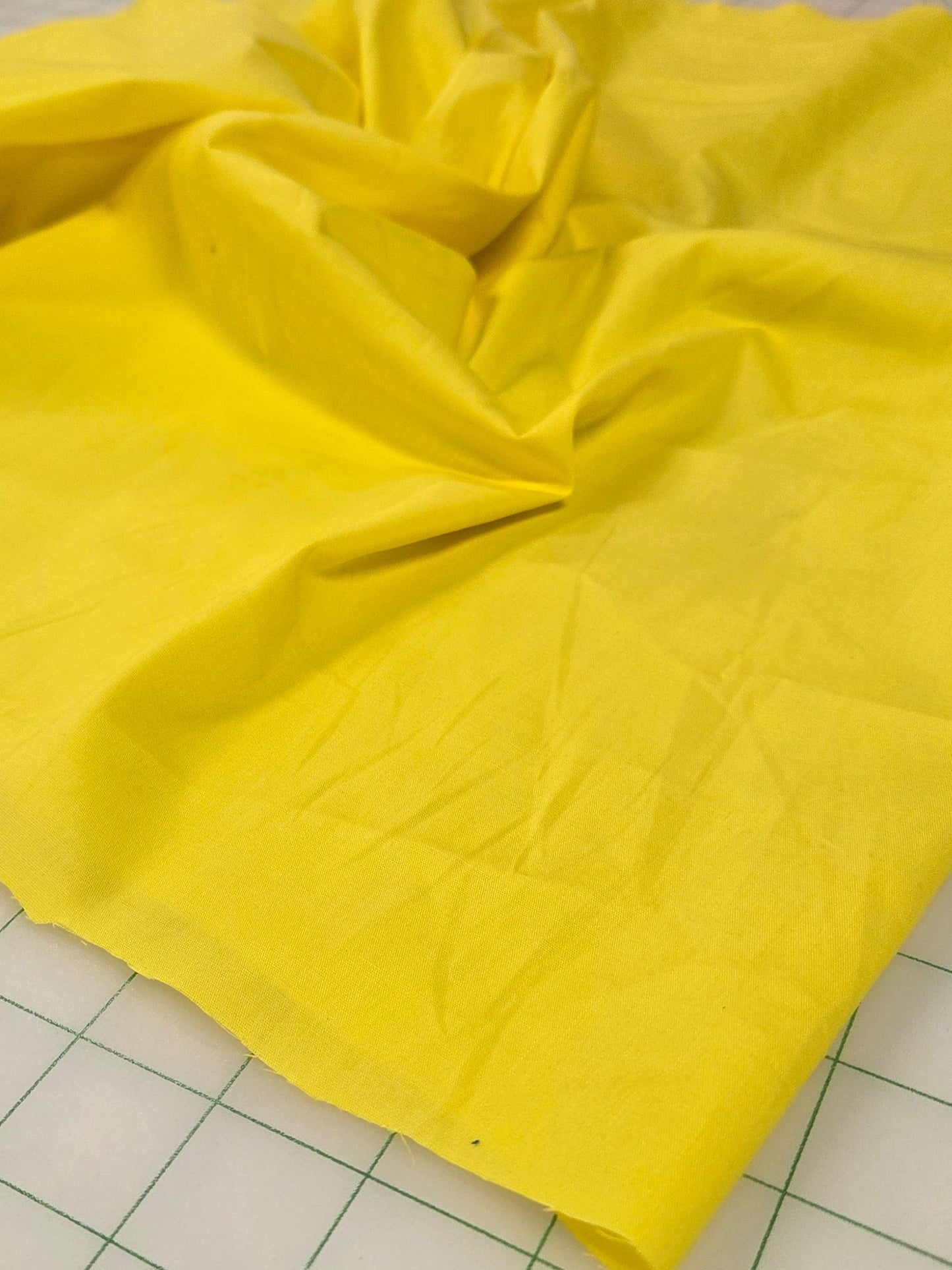 Yellow fabric on a cutting mat with grid lines